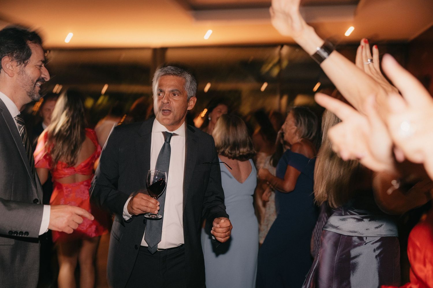 Lively wedding reception scene with dancing guests in formal evening wear.