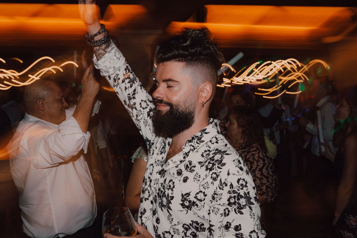 Guest dancing enthusiastically at wedding reception wearing floral print shirt.