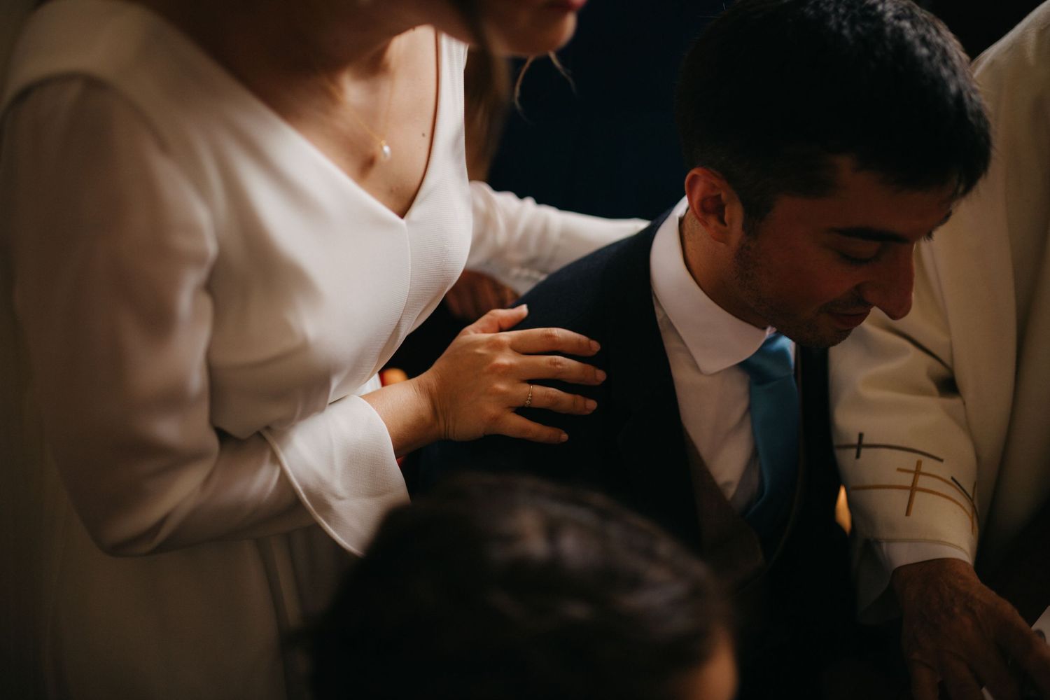Intimate moment shared during a wedding ceremony as guests gather around in prayer.