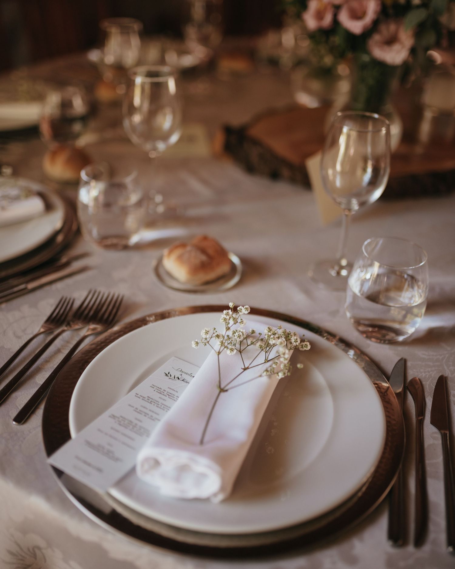 Elegant wedding table setting with white plates, wine glasses and delicate baby's breath floral details.