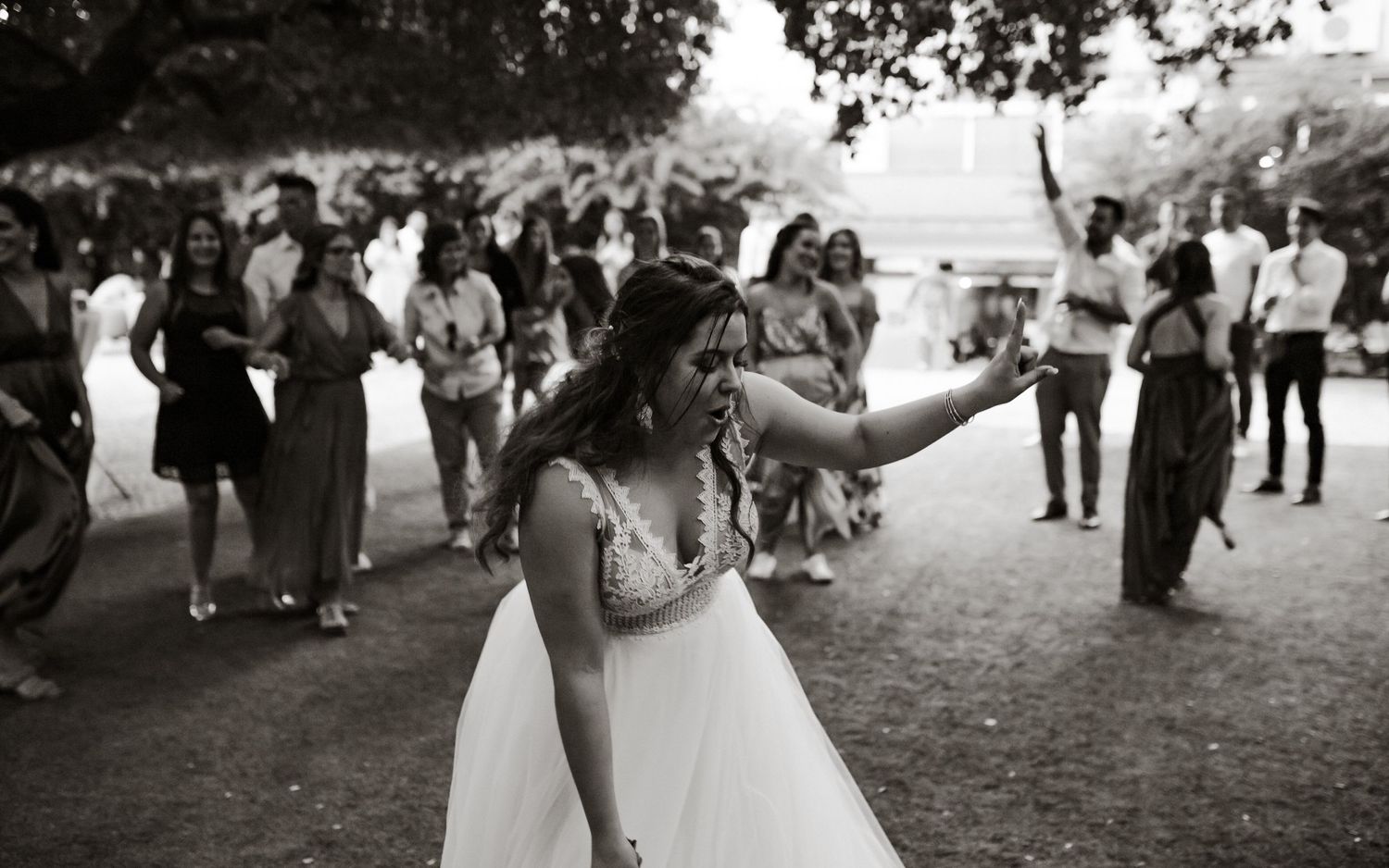 Wedding celebration with dancing guests in outdoor garden setting.