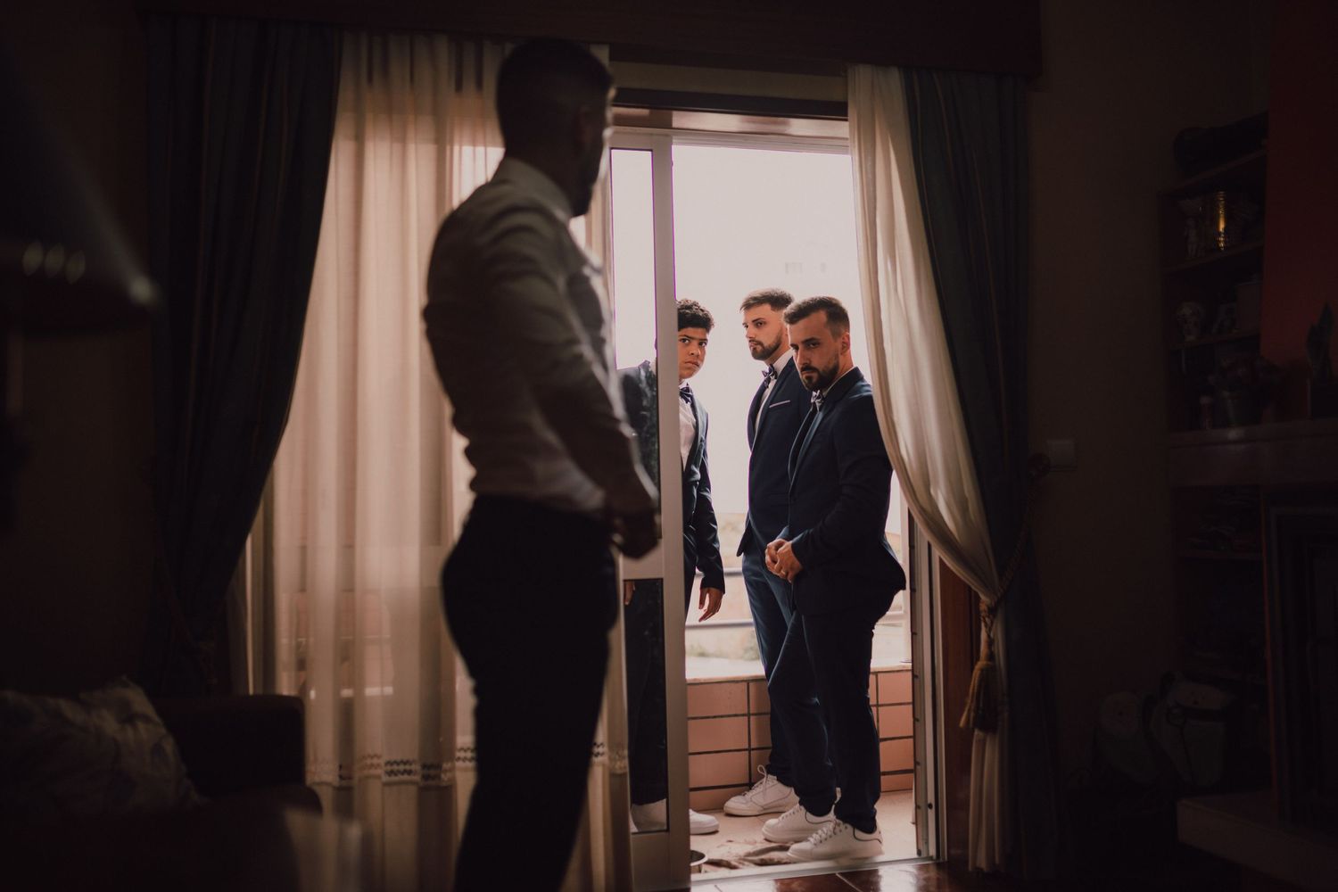 Silhouetted figures gathered in doorway during wedding preparations.