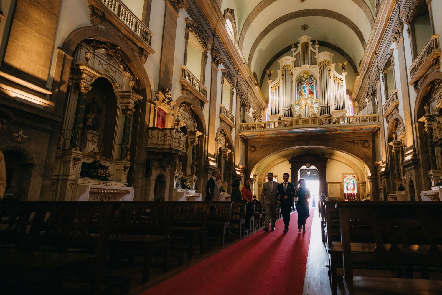 Grand cathedral interior with vaulted ceilings, pipe organ, and long red carpet aisle.