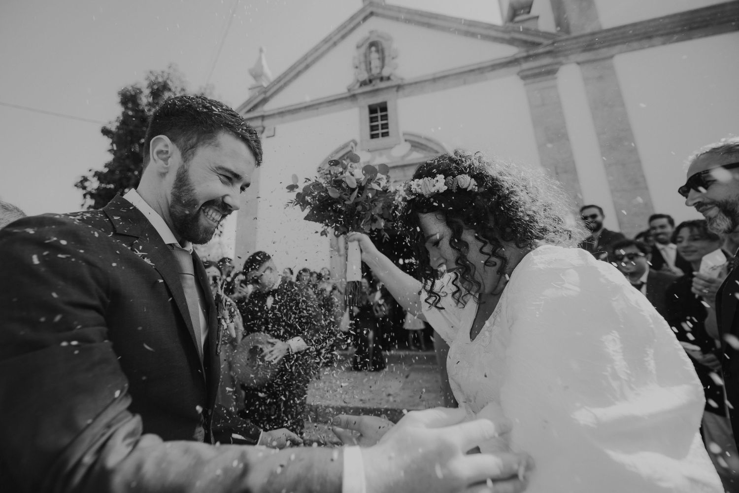 A couple shares joyful moment during confetti toss outside church.