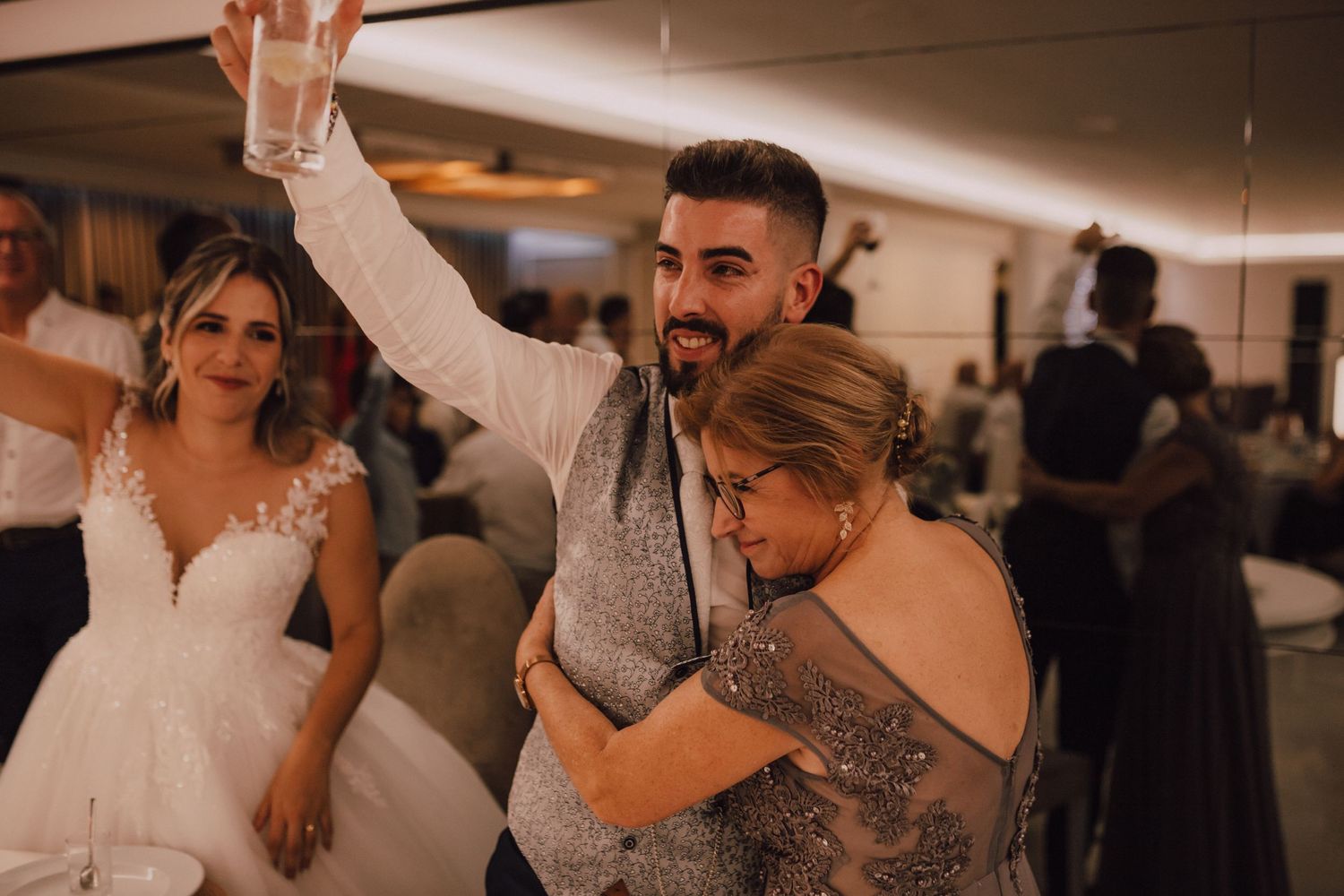 Wedding guests dancing and celebrating at indoor reception party.