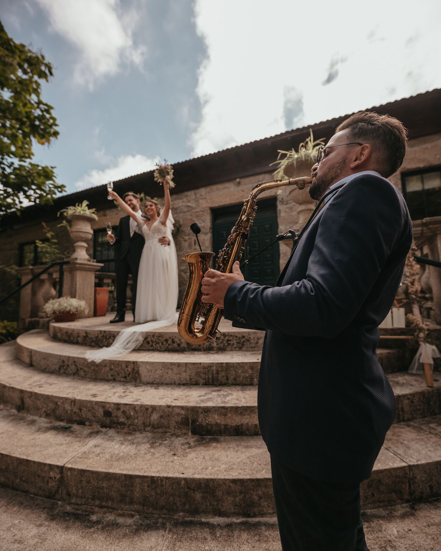 Wedding celebration on stone steps with live saxophone performance.