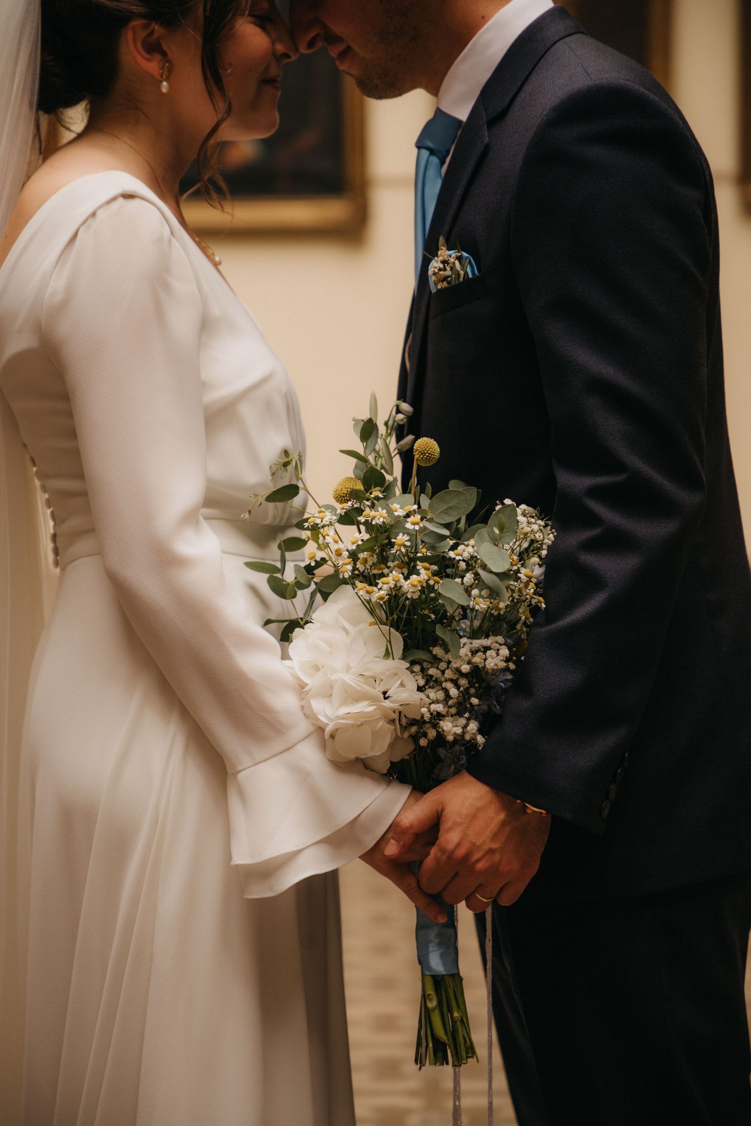 Intimate wedding portrait showing elegant bouquet and formal attire details.