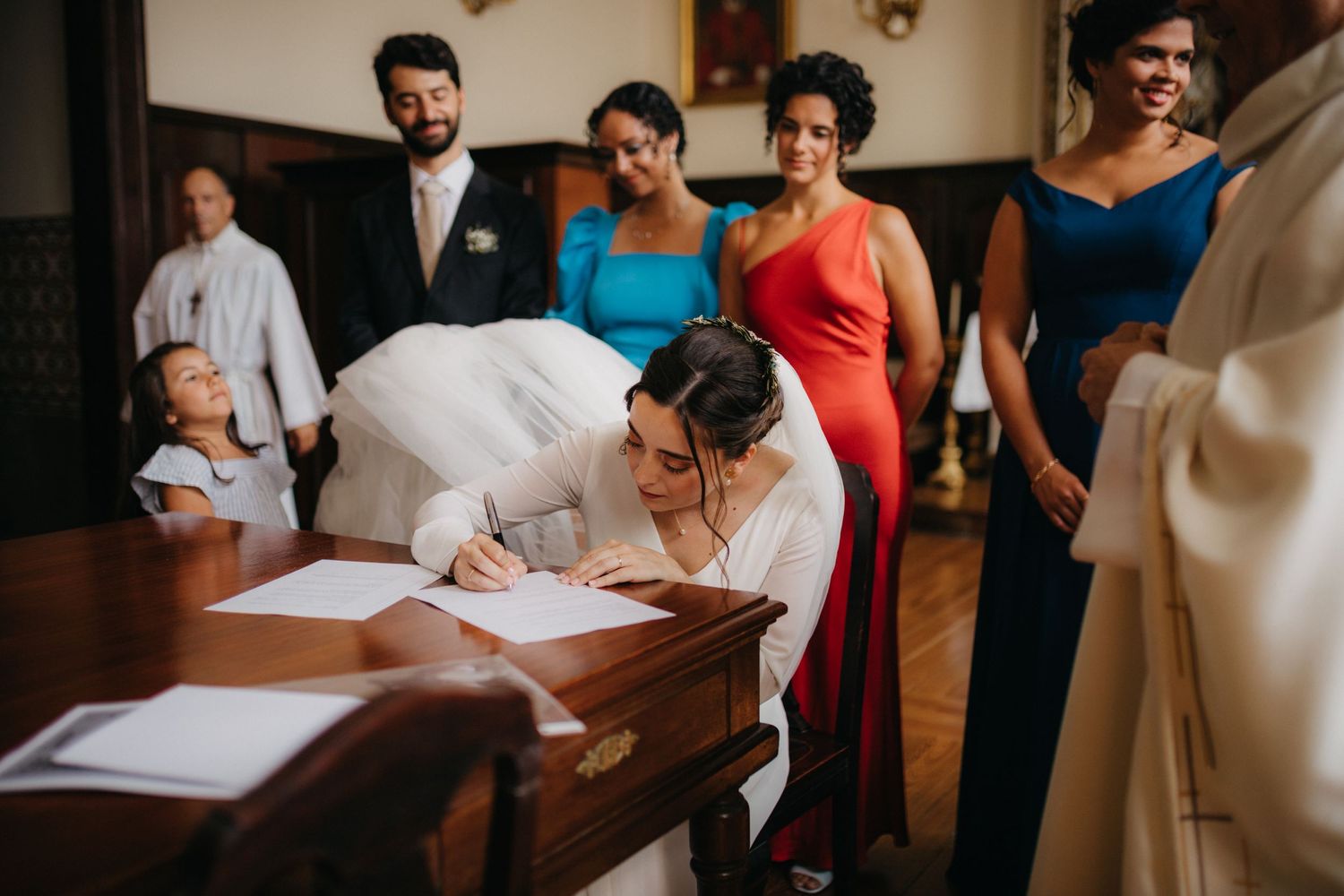 A signing ceremony takes place at a wooden desk during a traditional wedding.