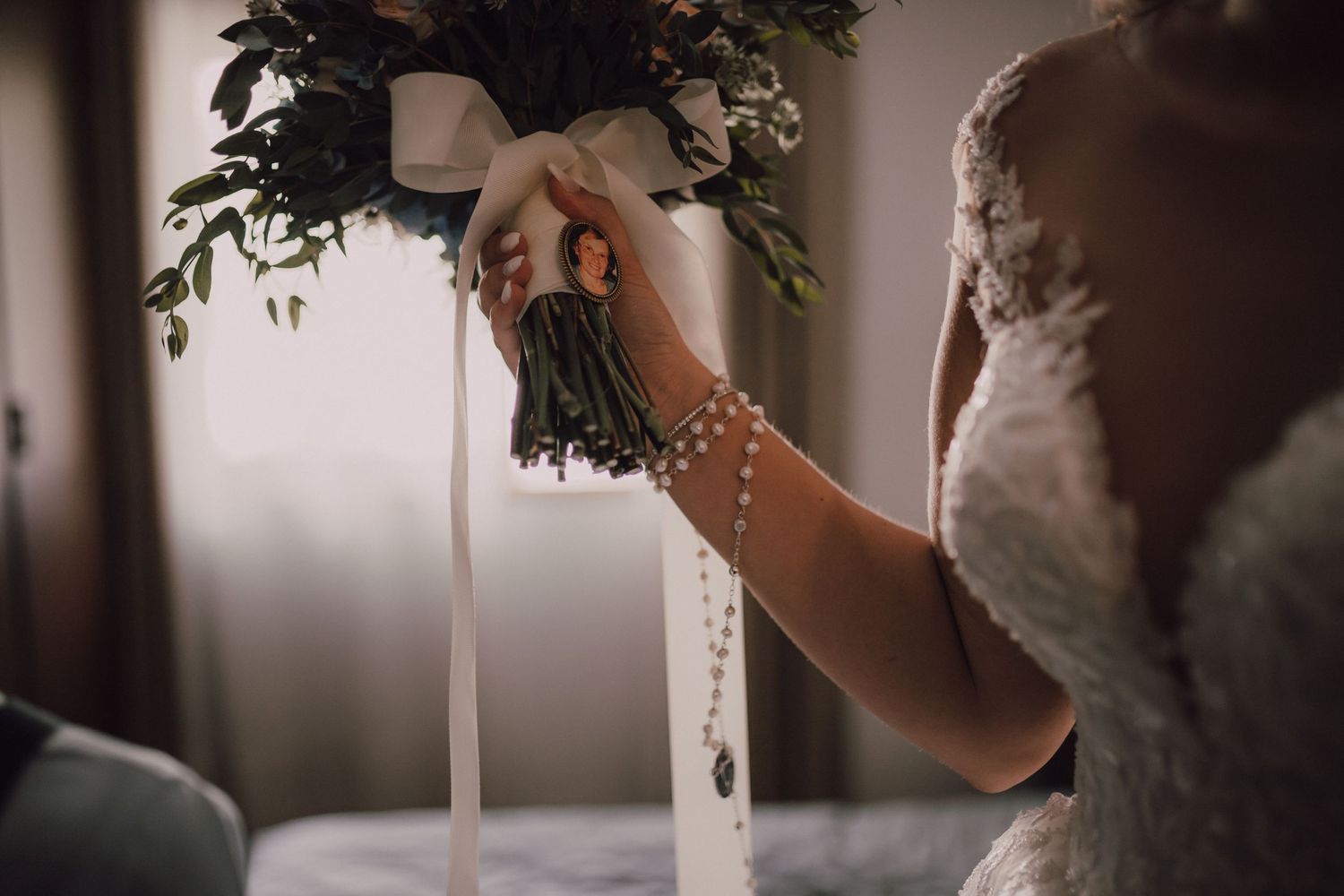 Detail shot of wedding flower arrangement being adjusted on white table setting.