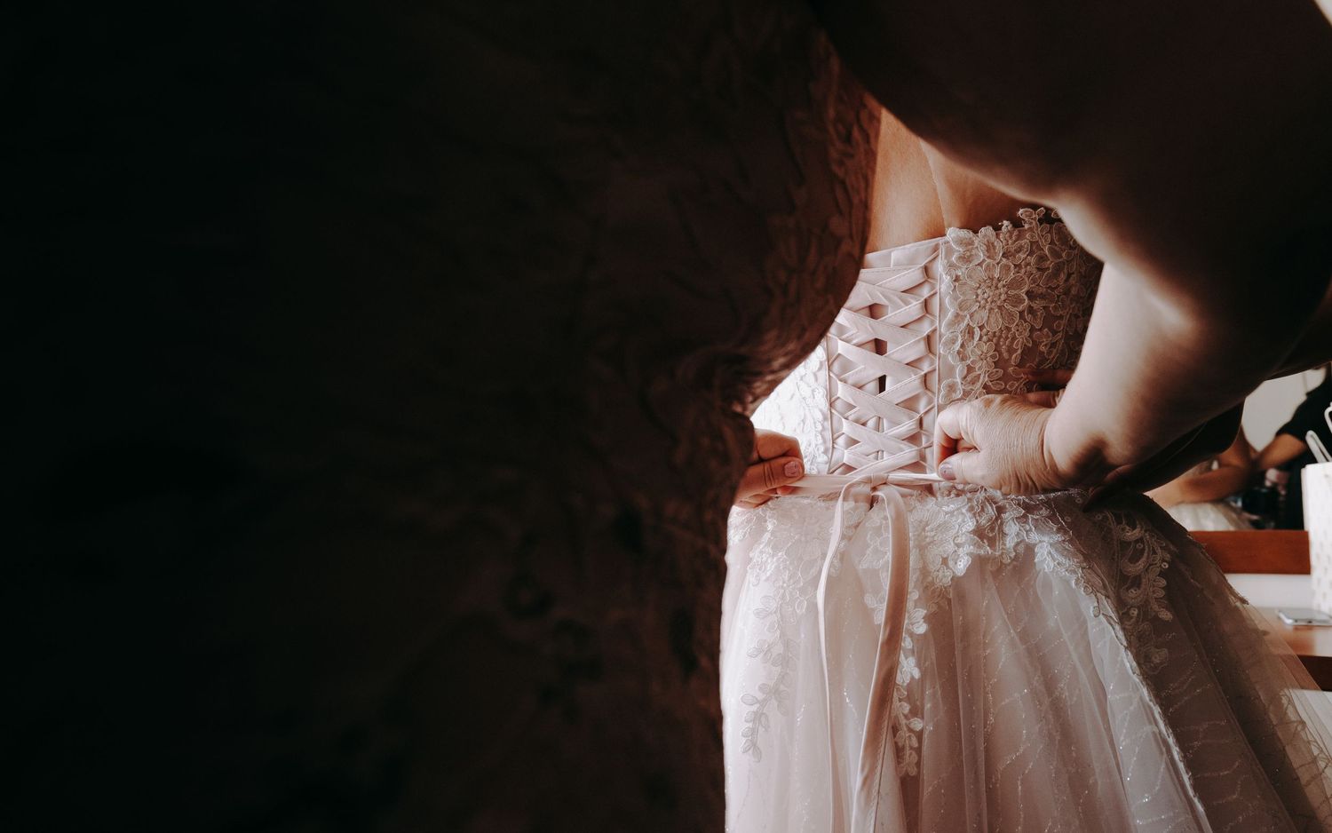 Close-up detail shot of intricate lace wedding dress being laced up.