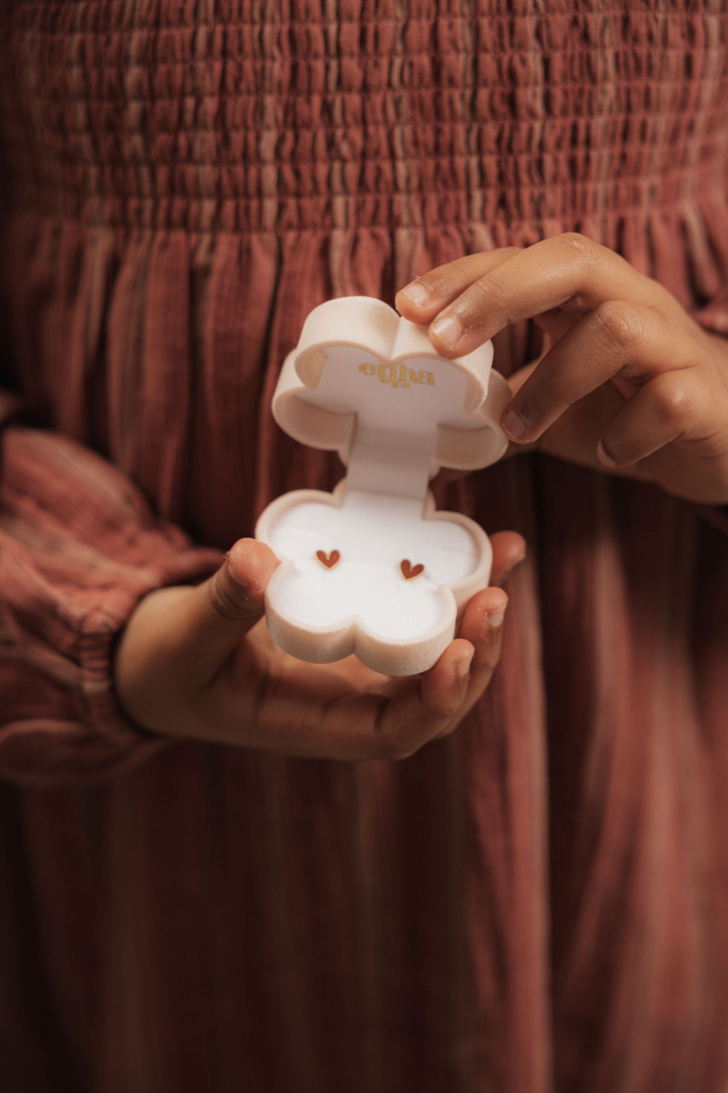 A small cloud-shaped LED light being held and displayed against a dark burgundy background.