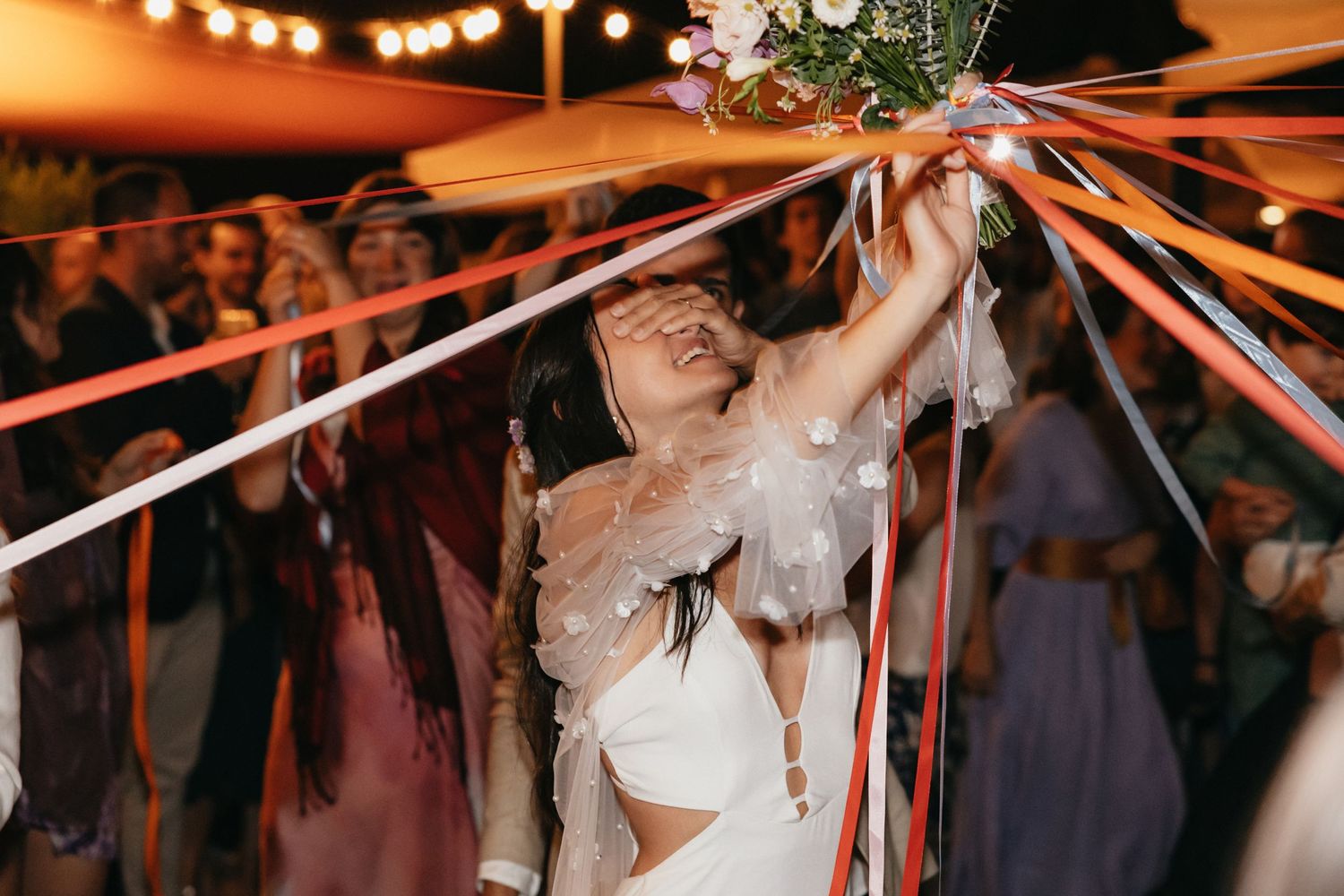 Wedding celebration with colorful streamers and guests gathering under evening lights.