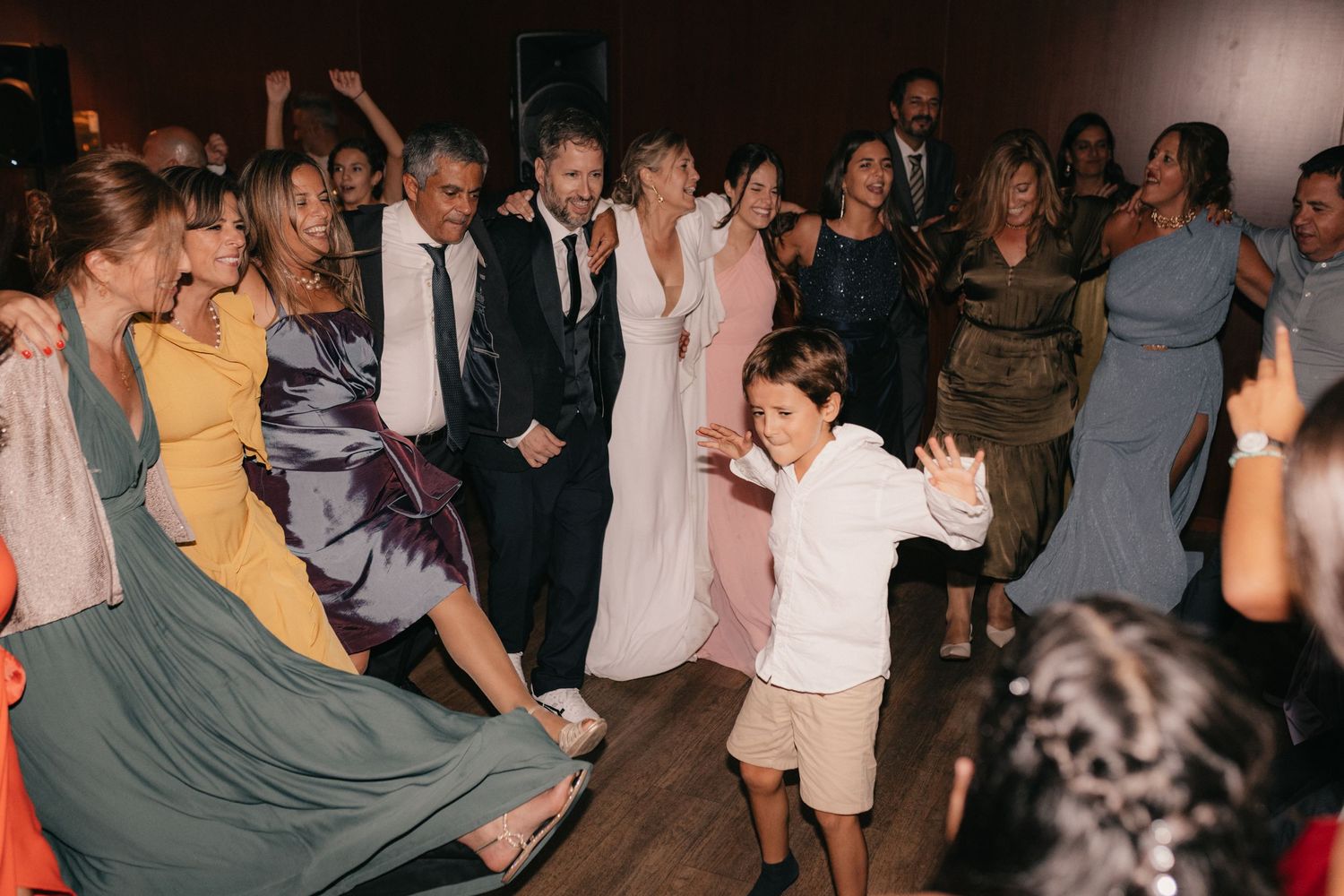 Wedding reception dance floor filled with guests in colorful formal attire.