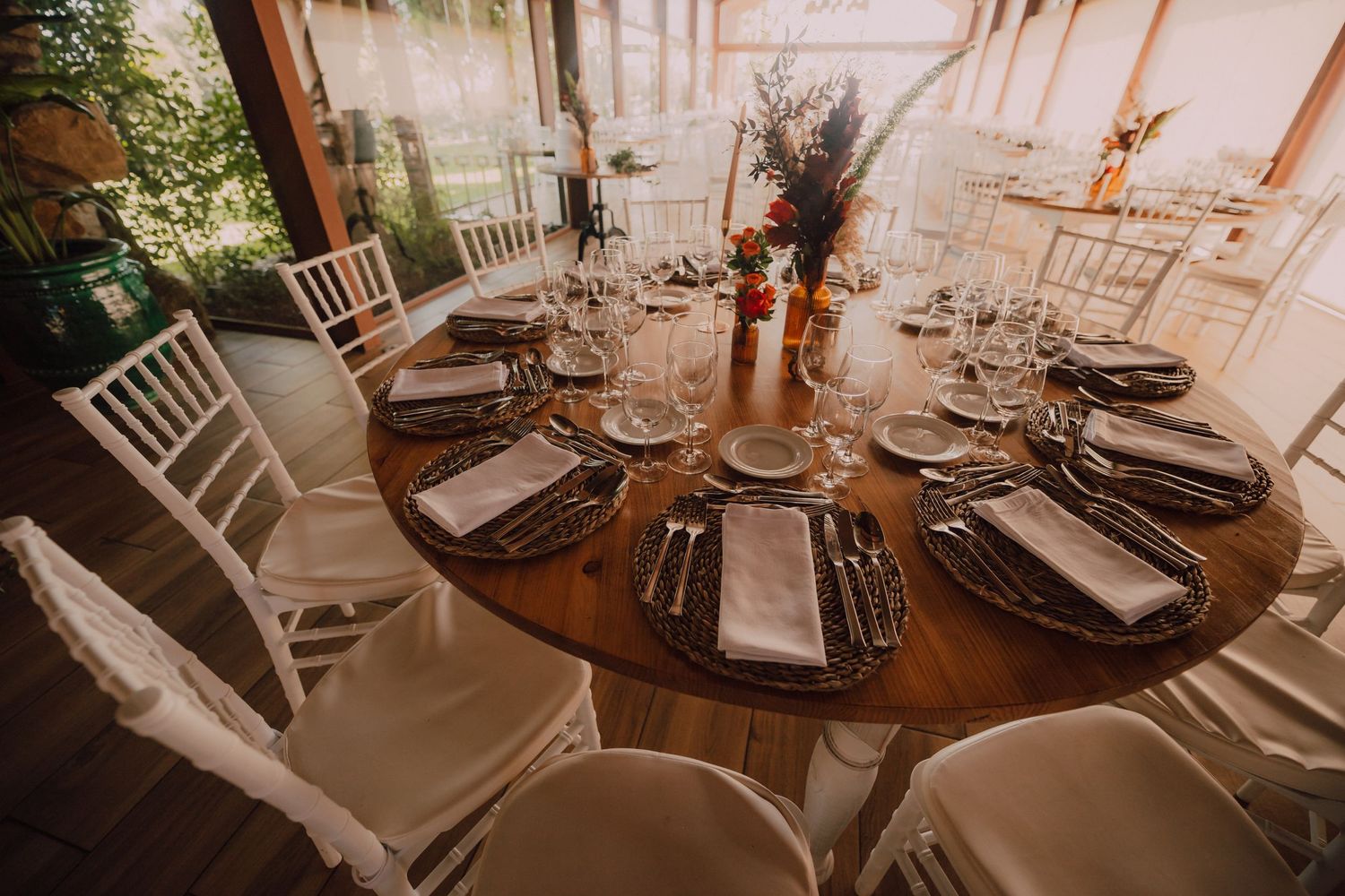 Round dining table set for wedding reception with white chairs and elegant place settings.