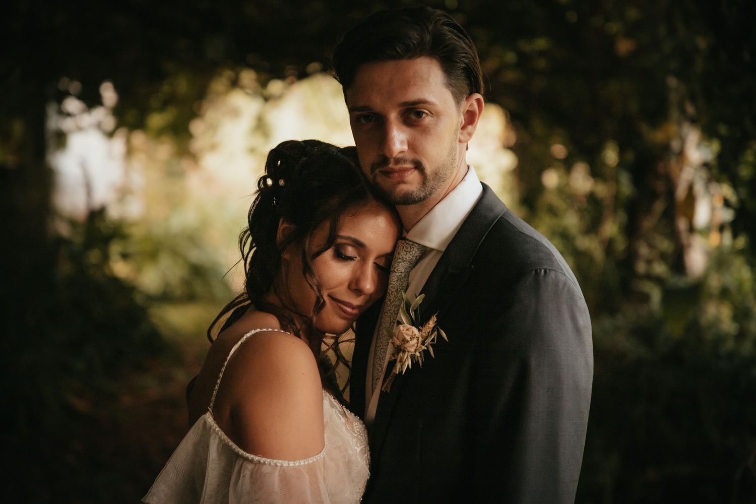 A romantic sunset portrait of newlyweds embracing in a dreamy forest setting.