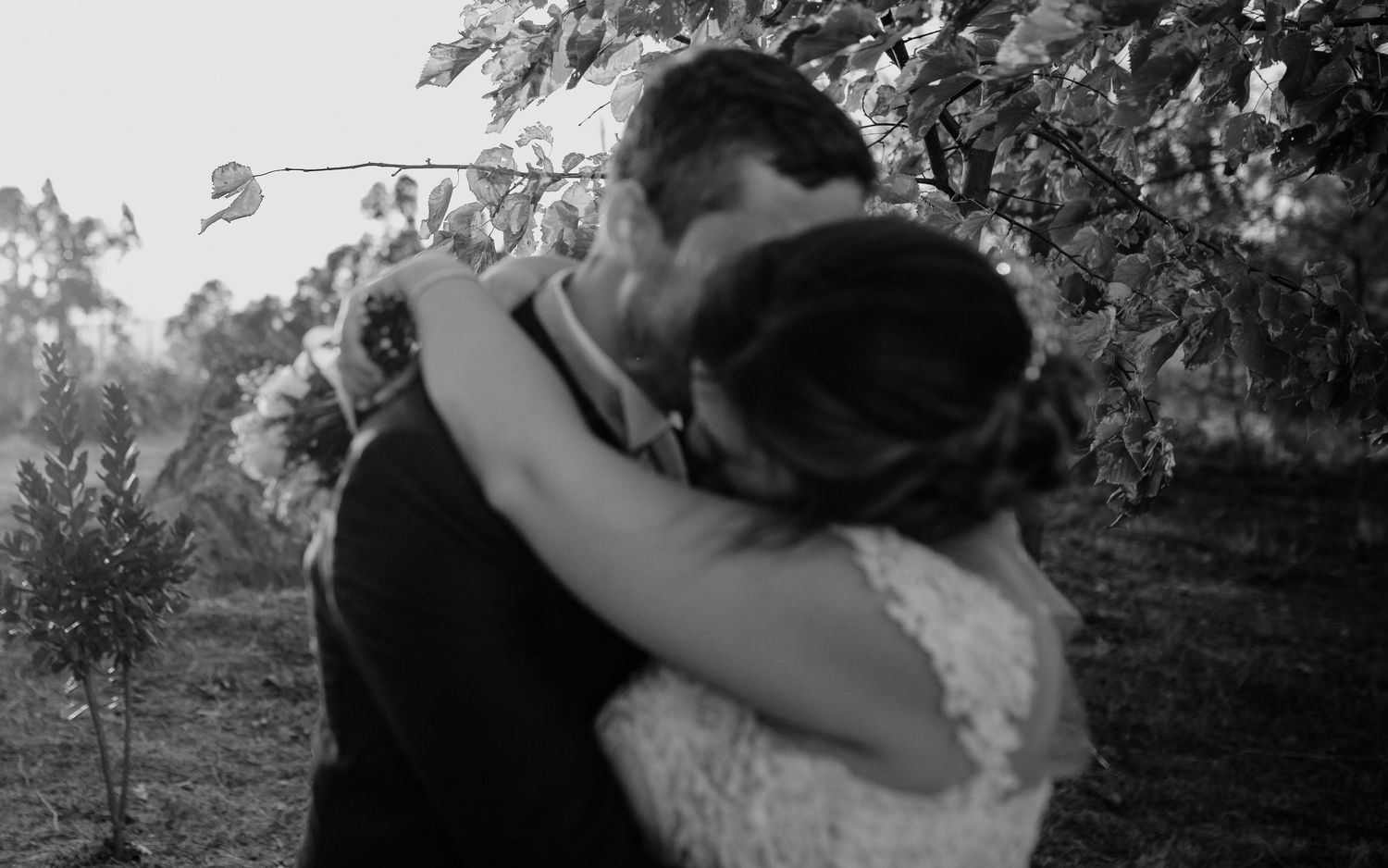 An intimate black and white portrait of a wedding couple sharing a tender moment outdoors.