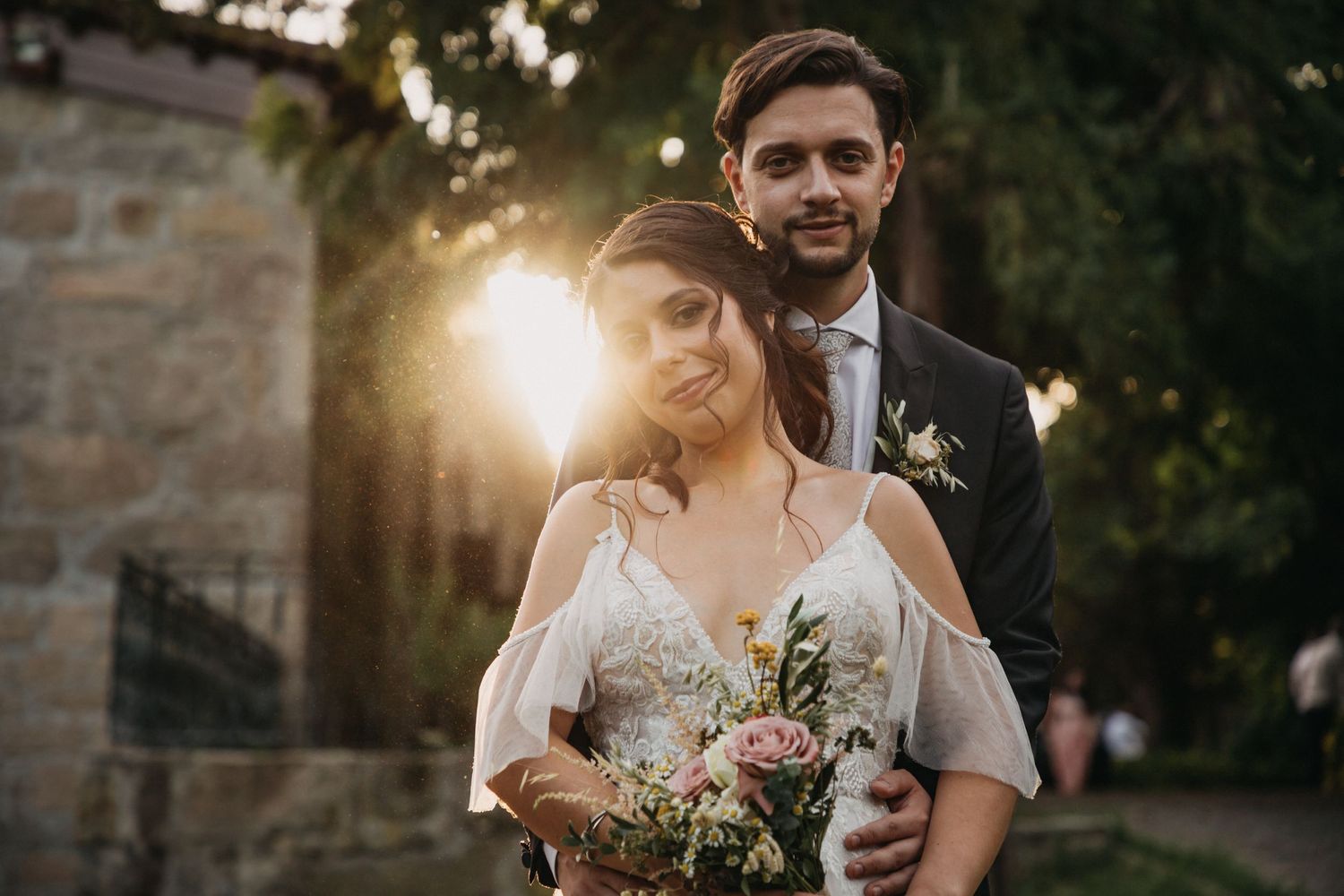 Romantic sunset wedding portrait with soft golden light filtering through stone architecture.