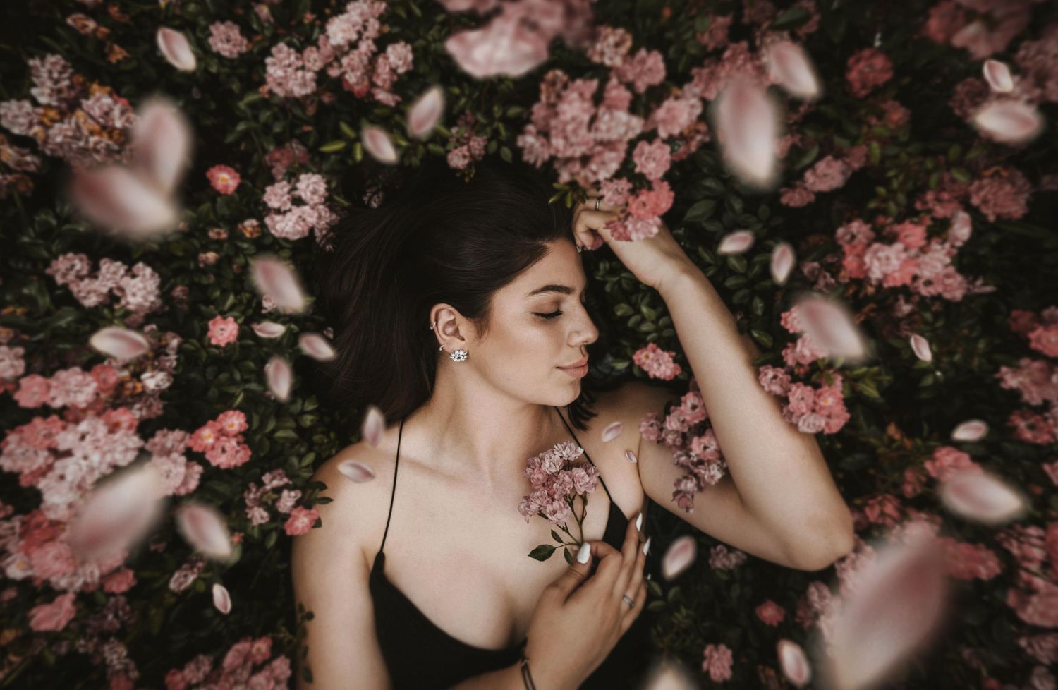 Pink cherry blossoms frame a dreamy portrait among falling petals.