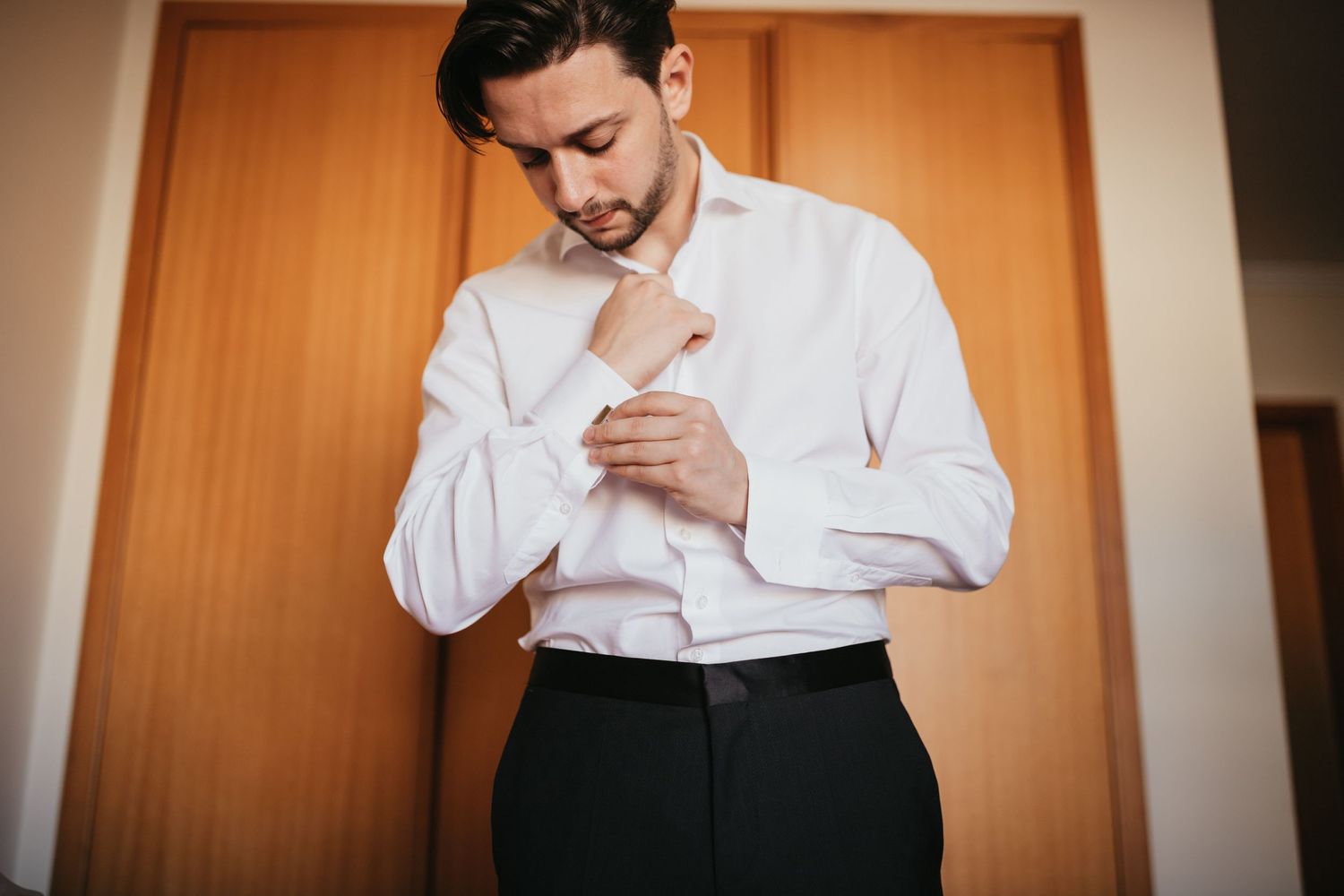 Person in white dress shirt buttoning sleeve cuff.