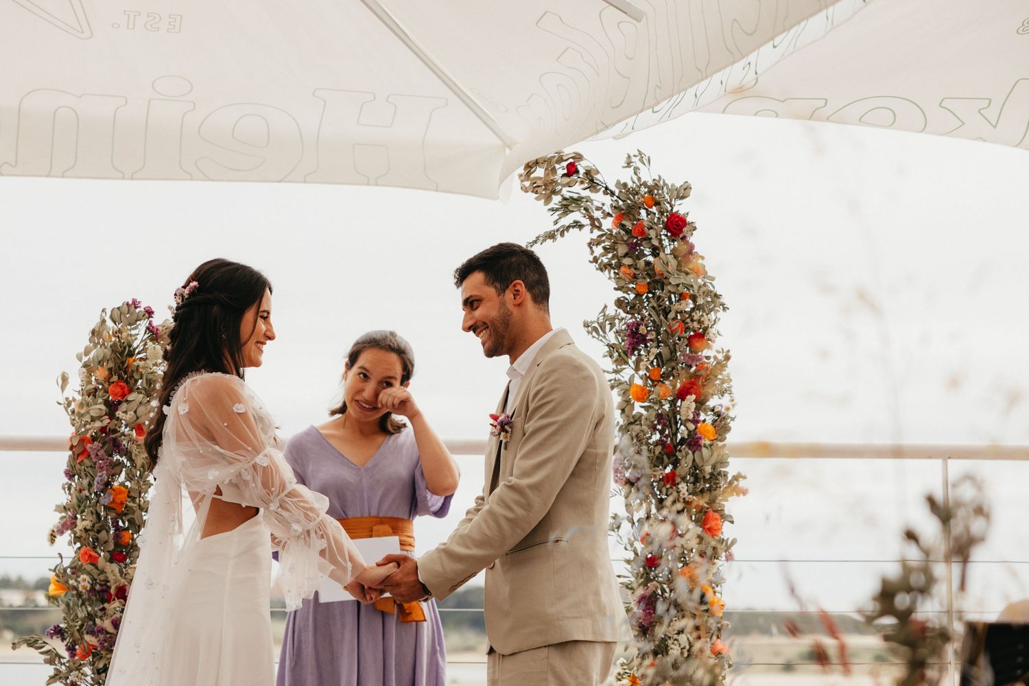 An intimate wedding ceremony taking place under a floral arch with autumn-colored decorations.