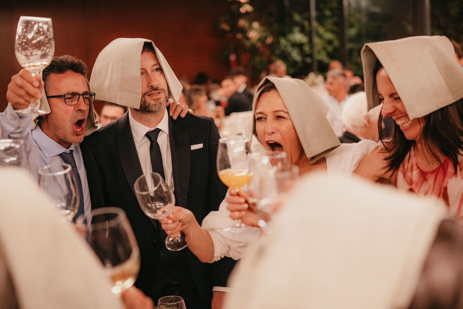 Wedding guests laughing and celebrating with drinks at a reception.