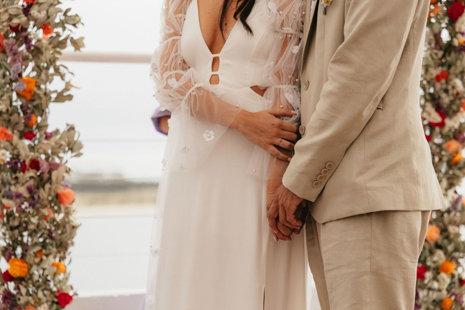 Close-up of couple during wedding ceremony beneath floral arch.