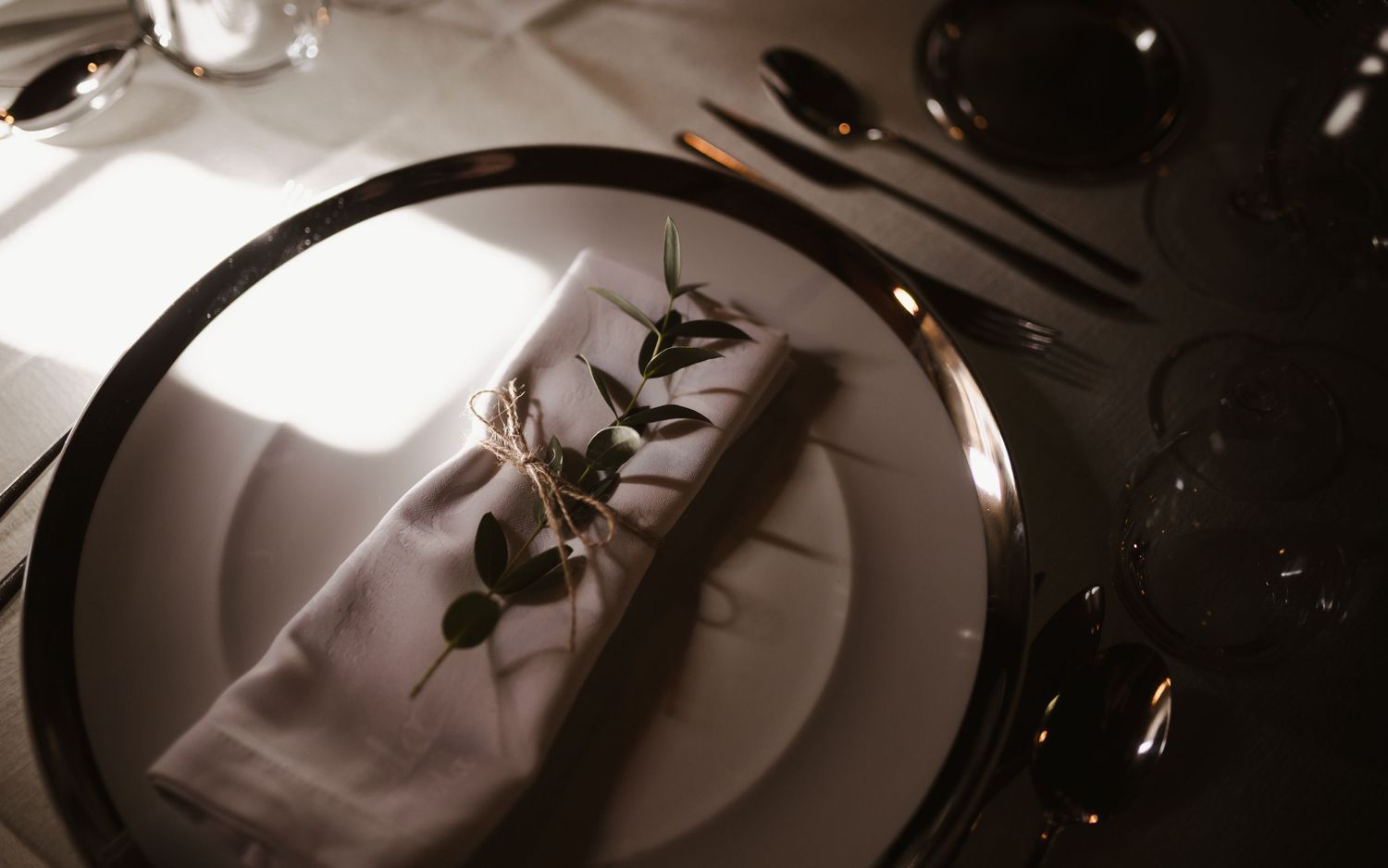 An elegant place setting features a black charger plate with delicate floral details.