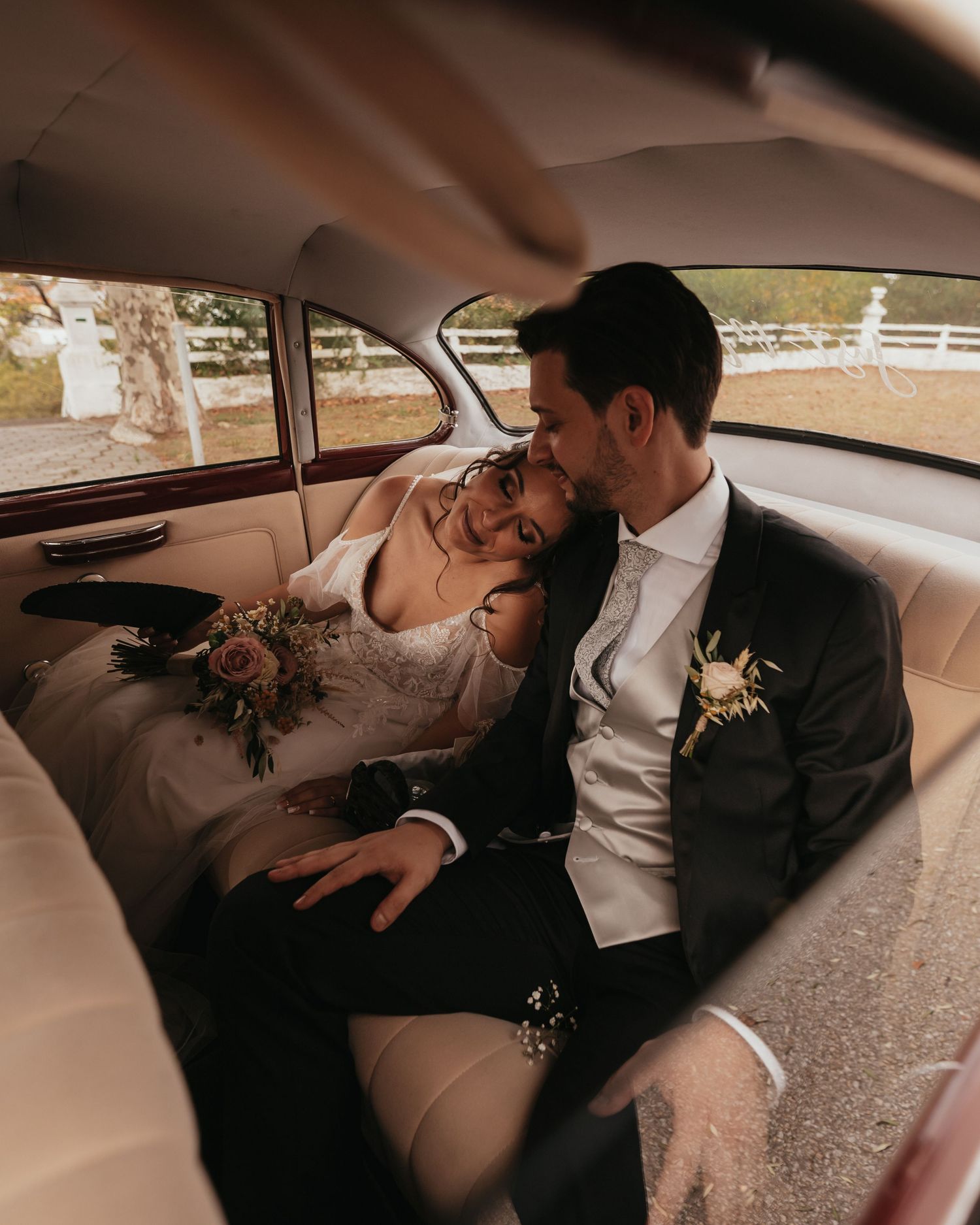 Romantic moment shared in vintage car with wedding bouquet.