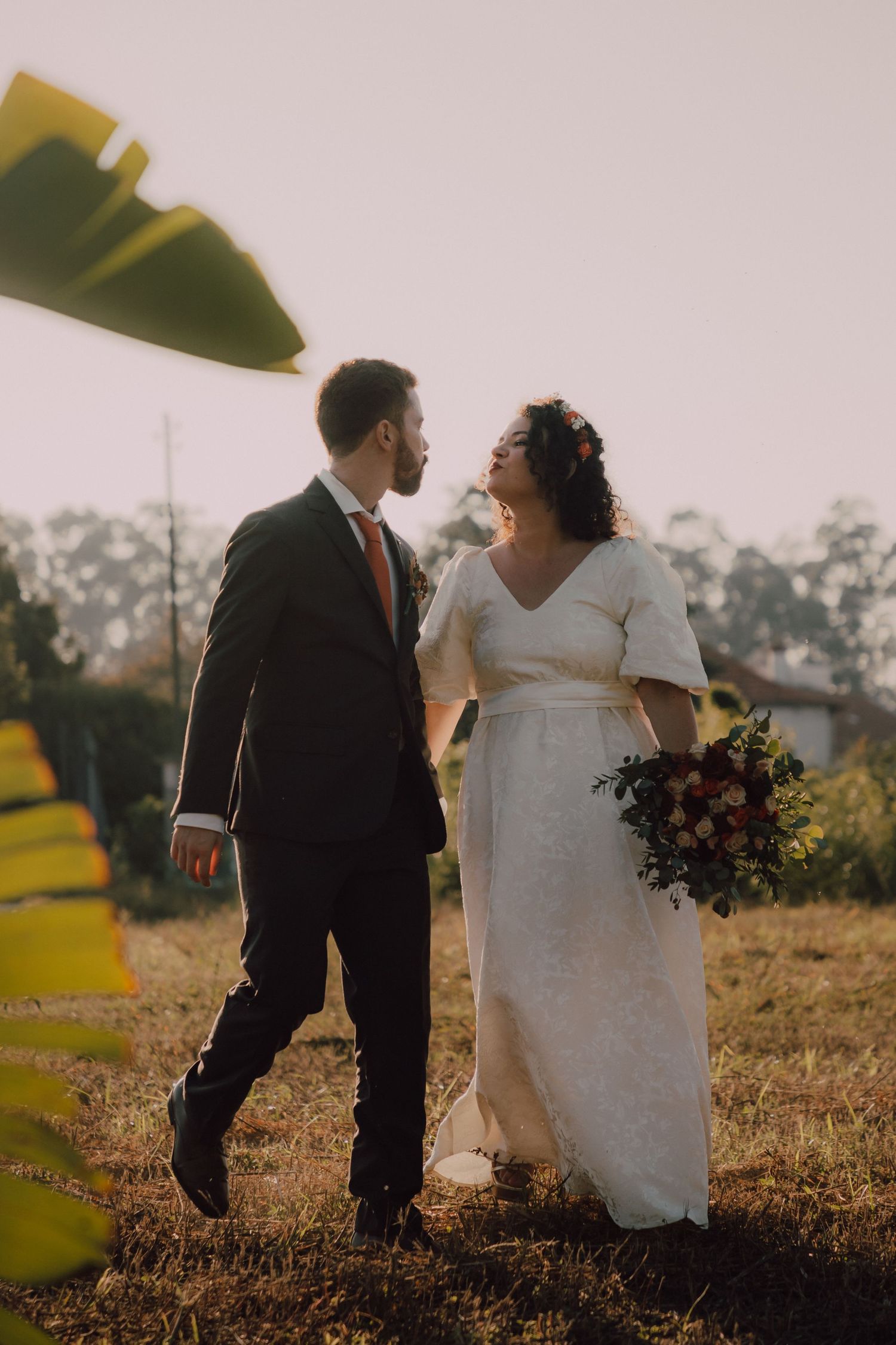 Couple shares intimate moment in sunlit field with autumn foliage.