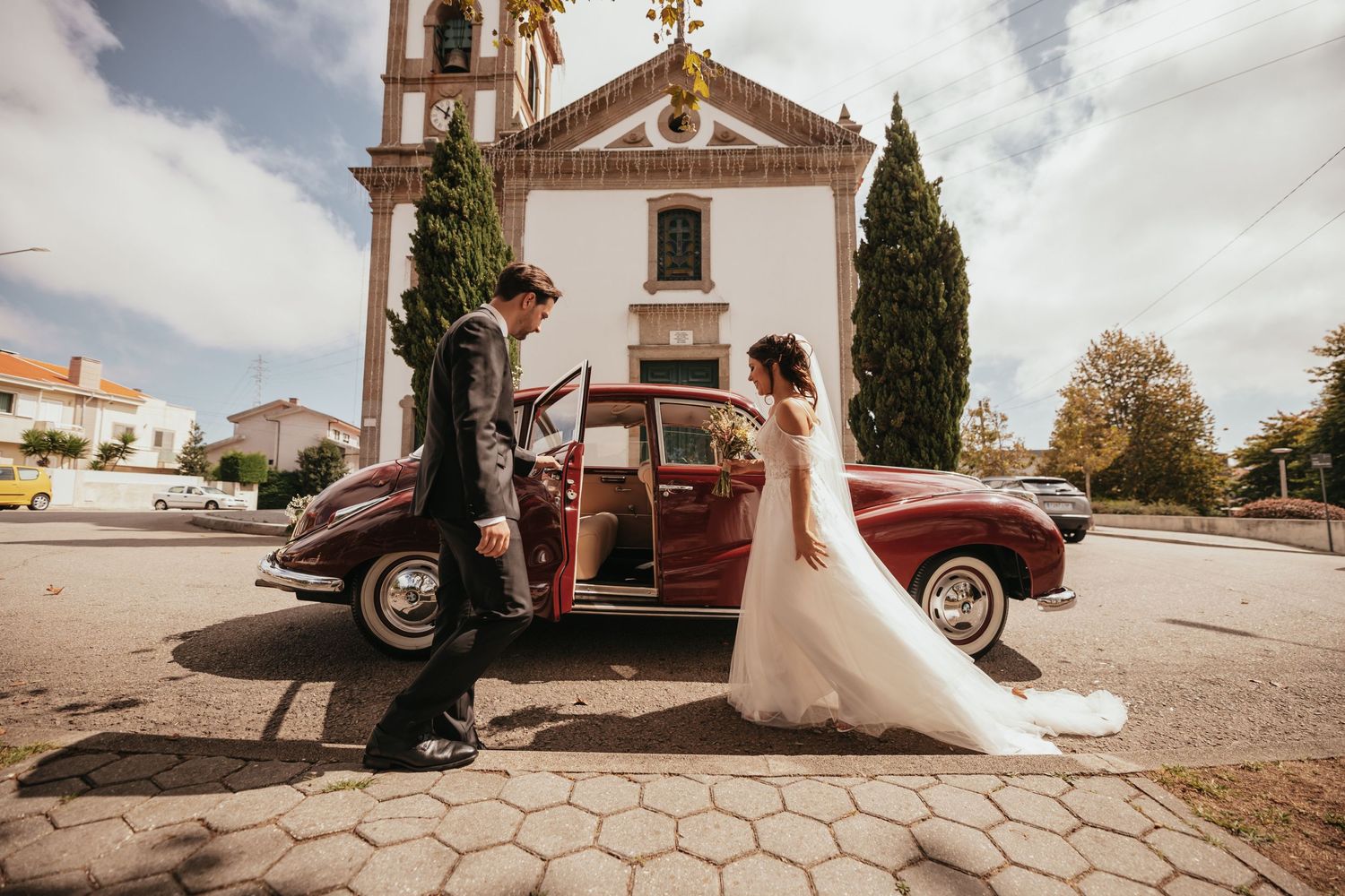 Vintage car wedding photo outside historic church with classic architecture.