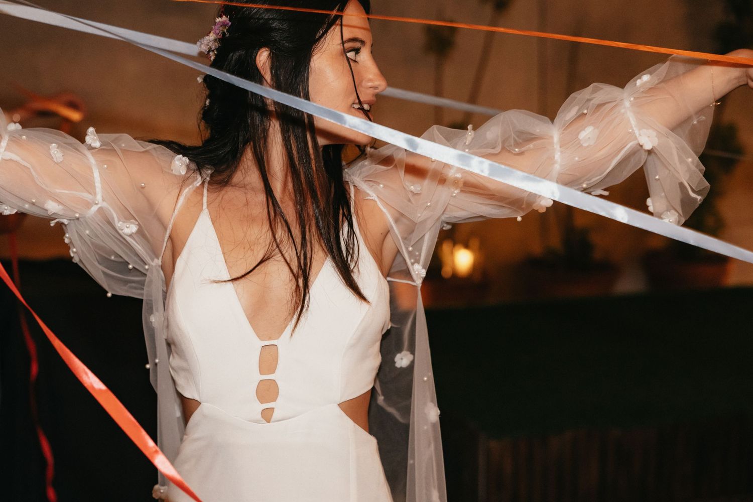 Artistic shot of a modern wedding dress with strappy details and flowing veil.