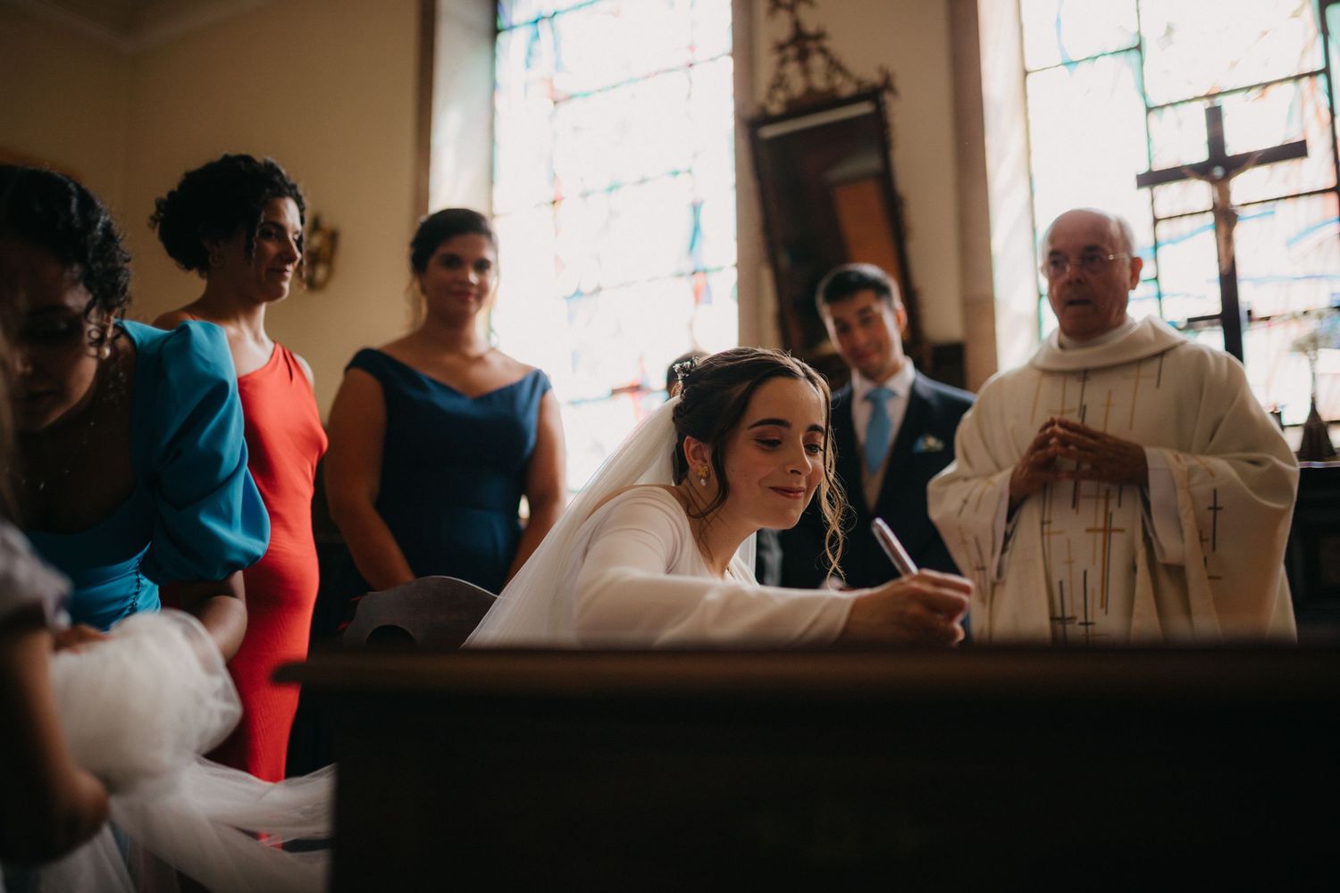 A wedding ceremony in progress at a traditional church with stained glass windows.