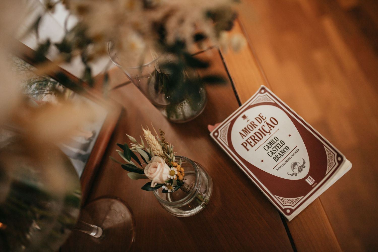 Wedding decor detail featuring dried flowers and vintage book on wooden surface.
