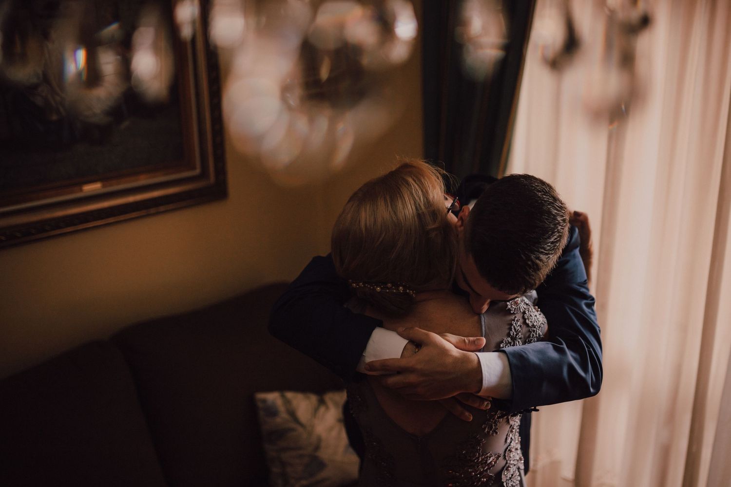 An intimate embrace captured in a dimly lit room with warm tones.