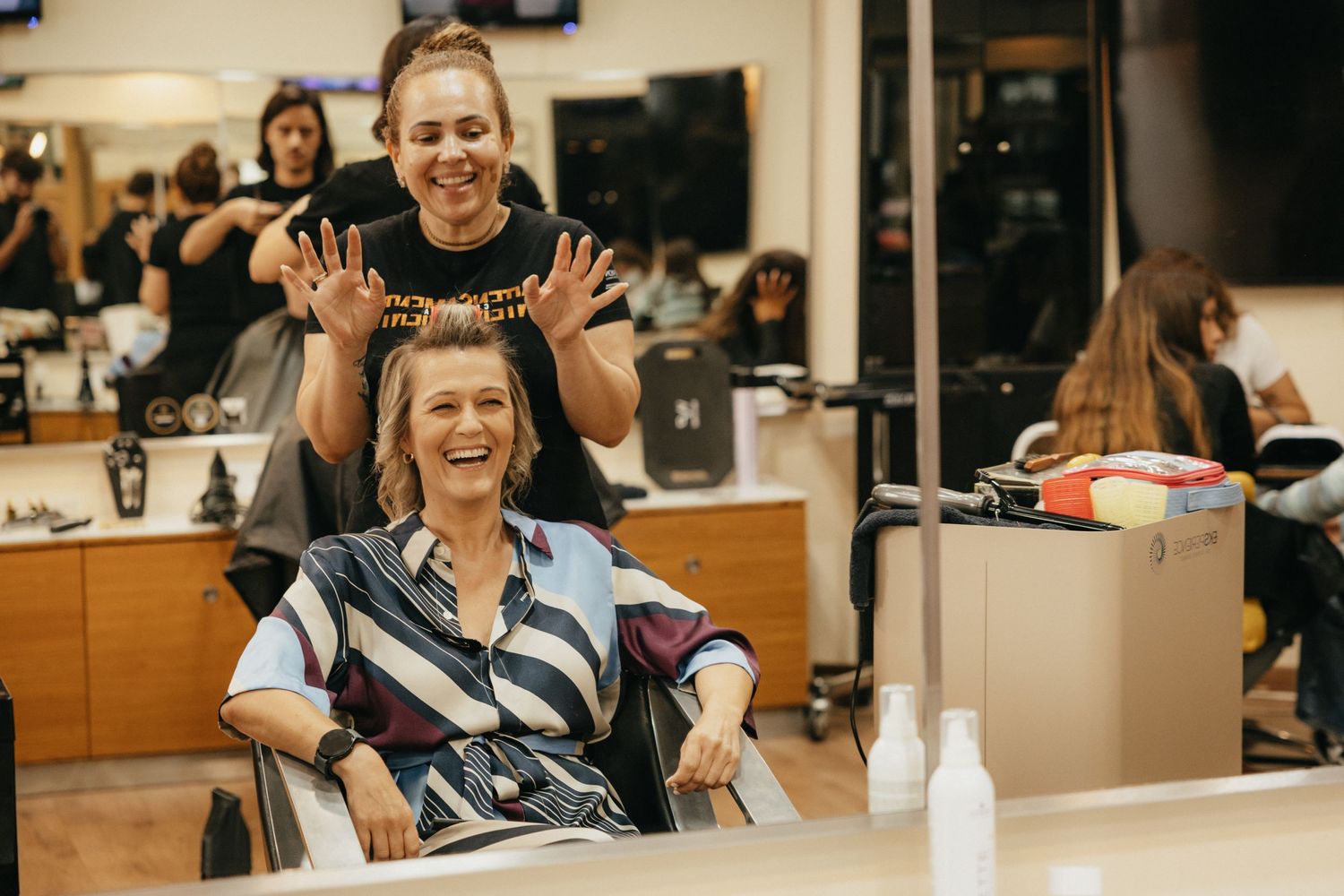 Candid moment of joy and laughter during wedding preparations in salon setting.