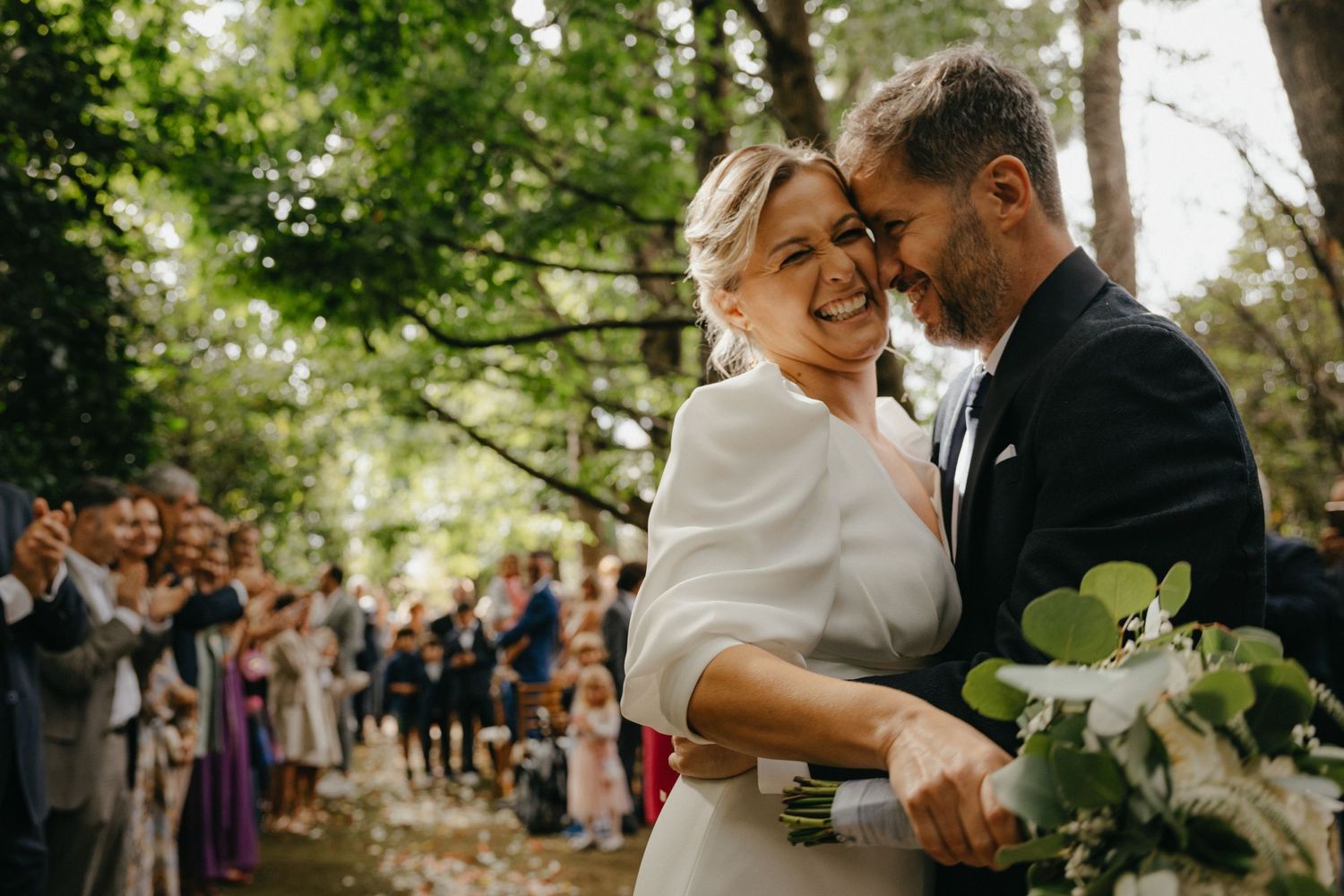 Outdoor wedding ceremony moment with guests watching in garden setting.