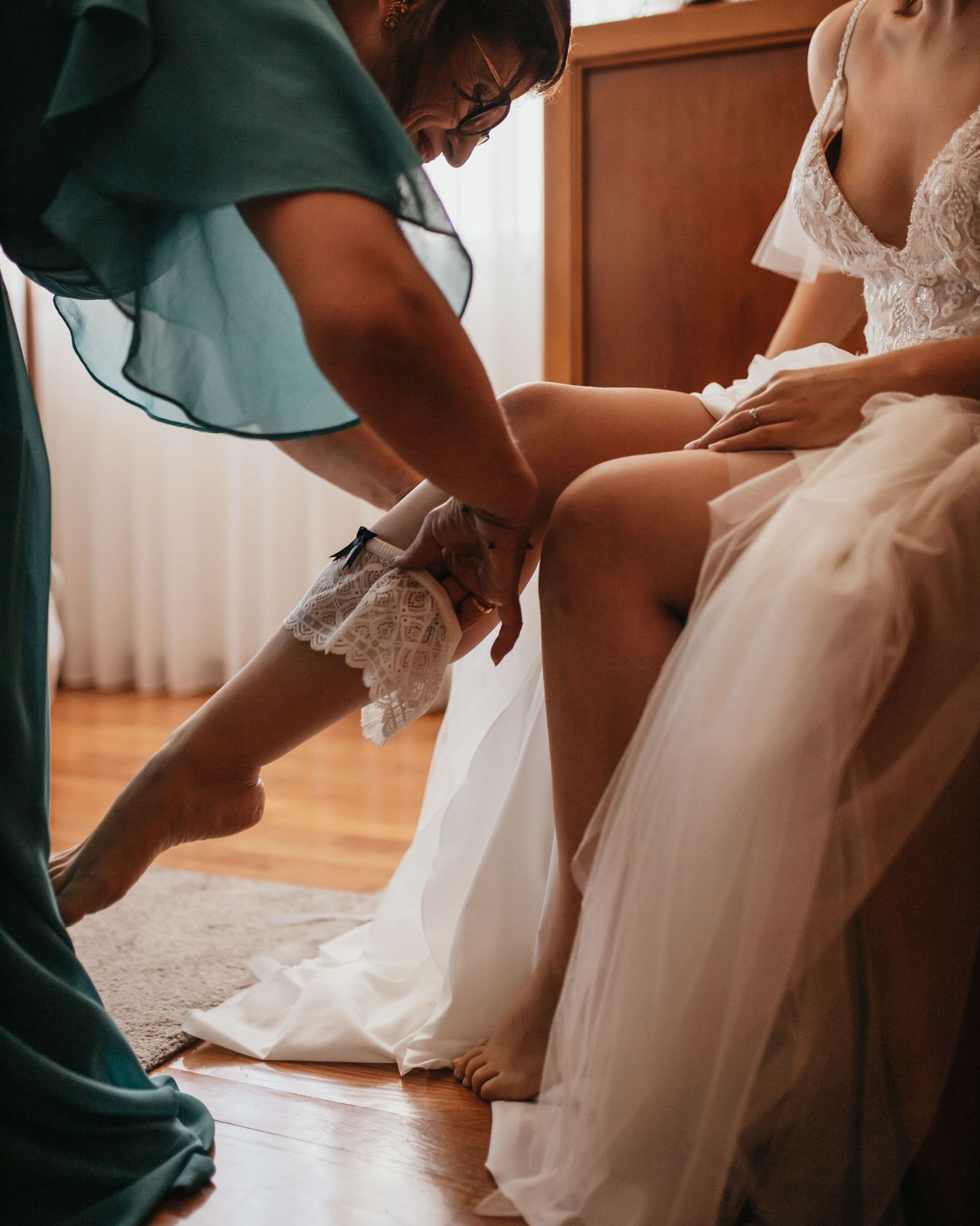 Detail shot of bride getting help with wedding garter during preparation.