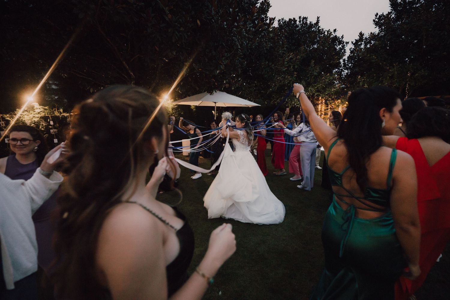 Wedding party celebrates with outdoor dancing at night under string lights.