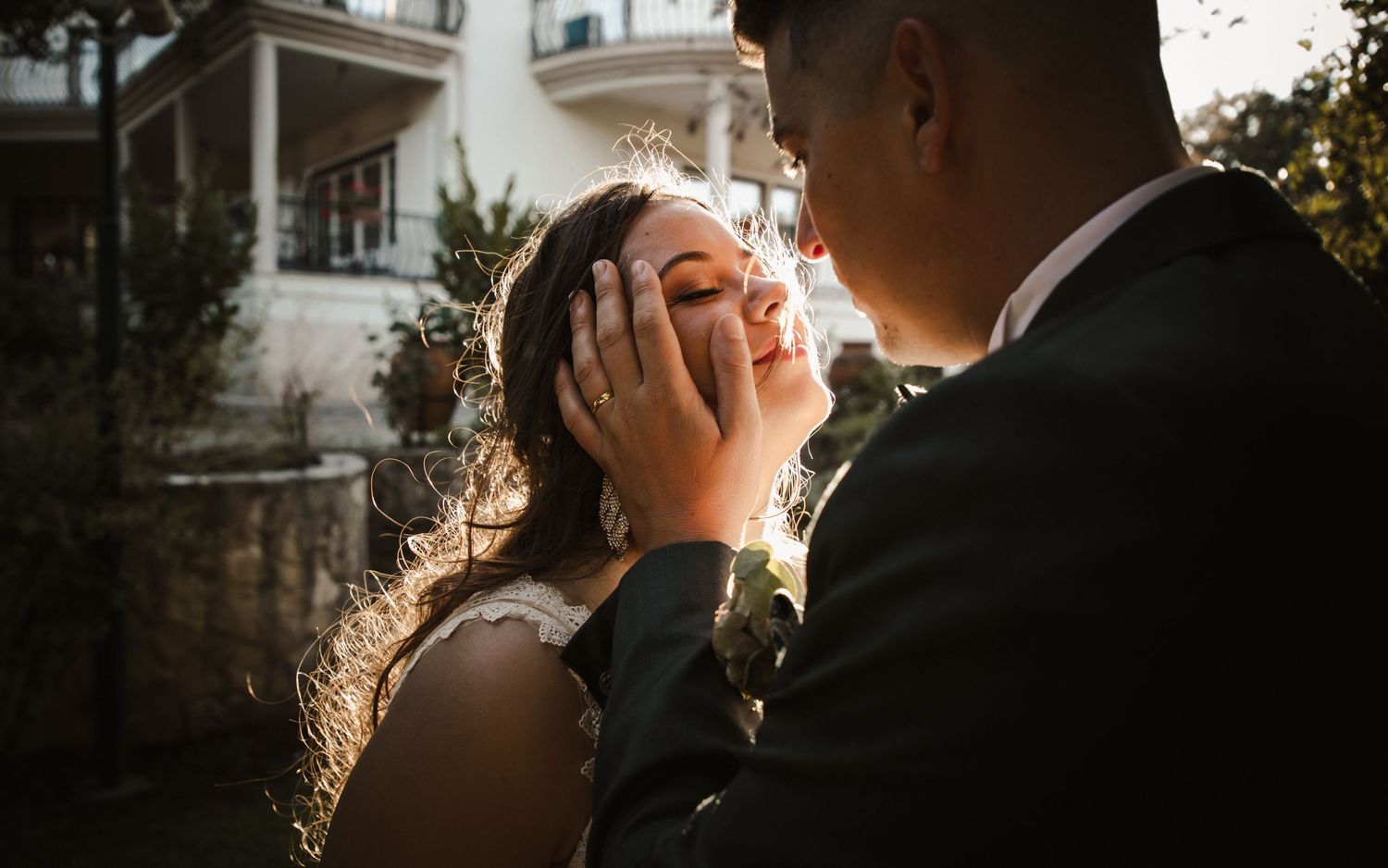 Tender moment between wedding couple backlit by golden sunlight.