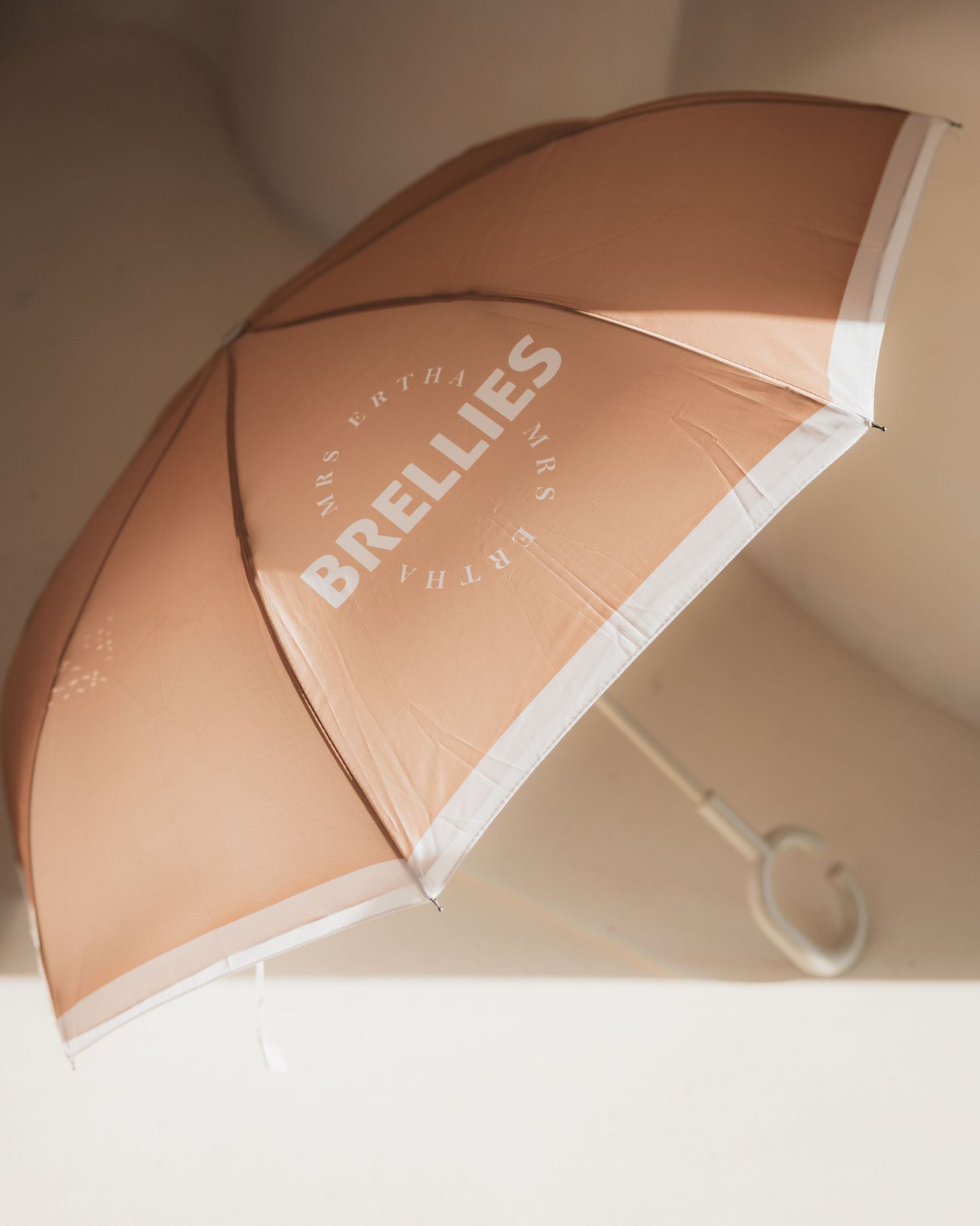A series of beige umbrellas arranged in a minimalist composition against a light neutral background.