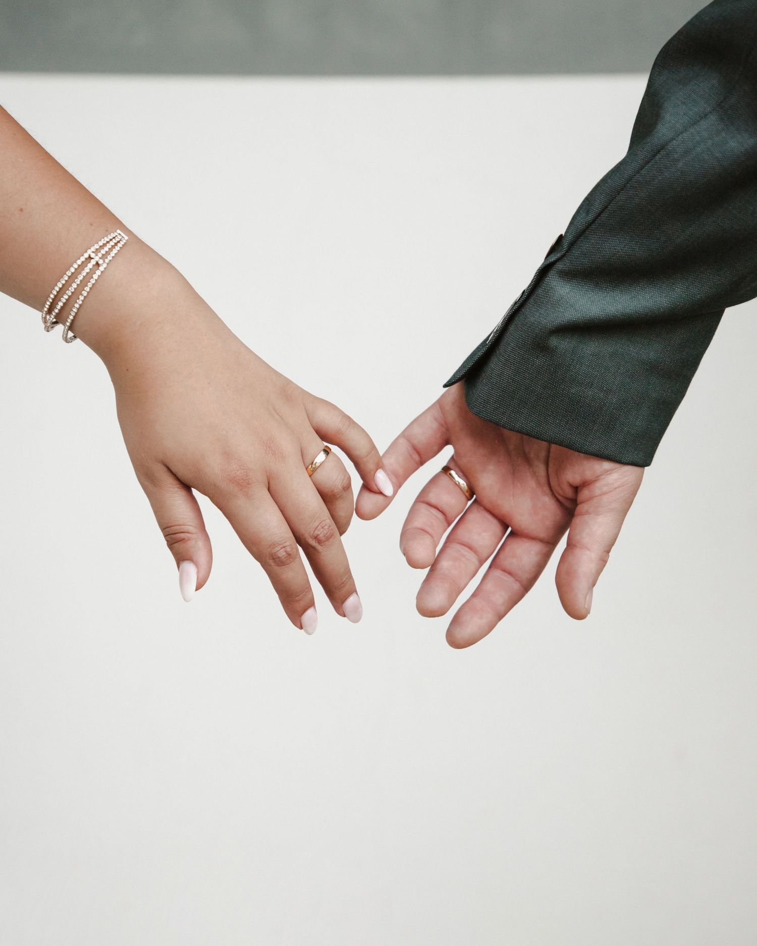 Two hands reaching toward each other with delicate bracelet detail.