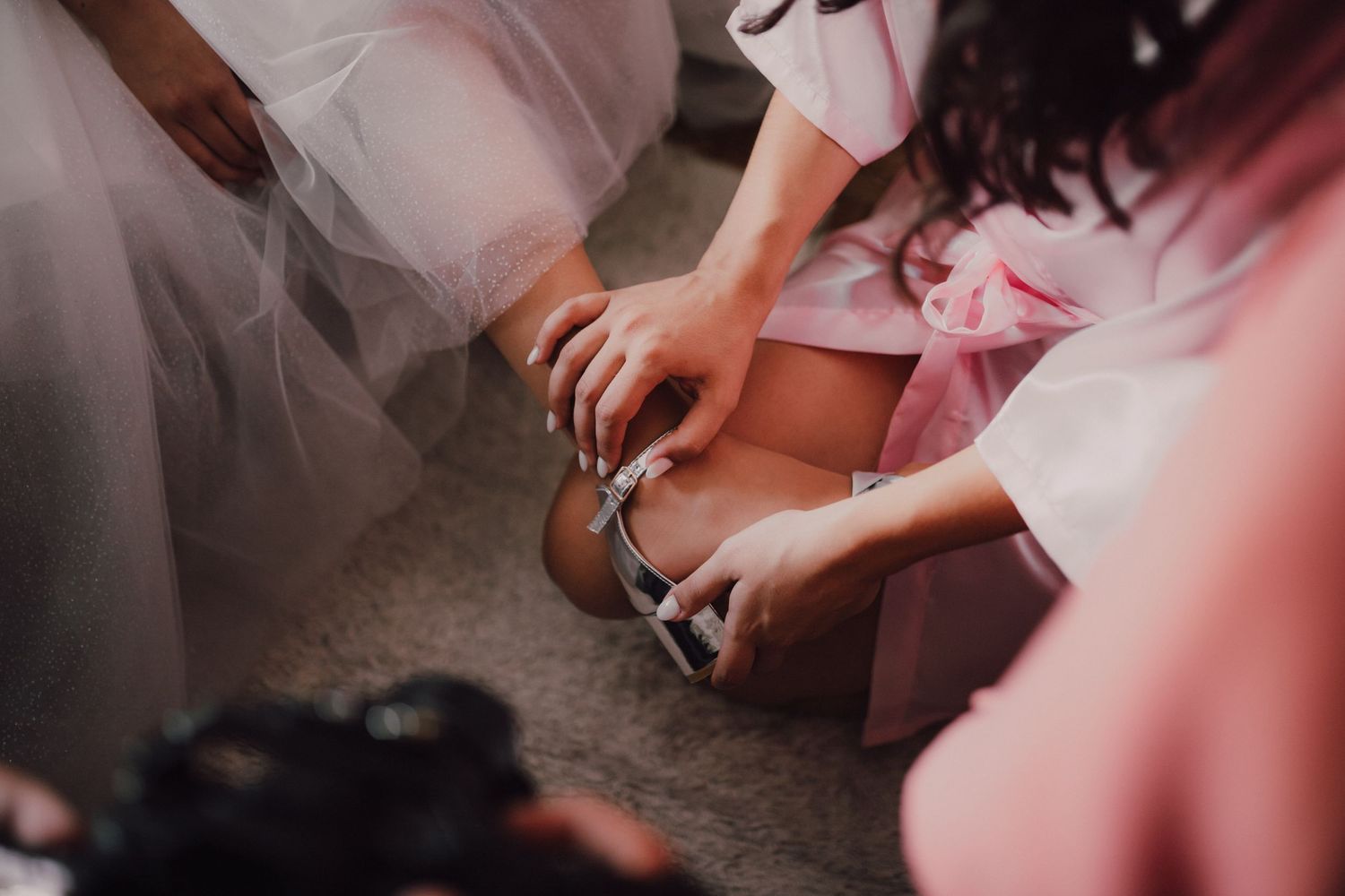 Close-up shot of hands helping with wedding shoe fitting.