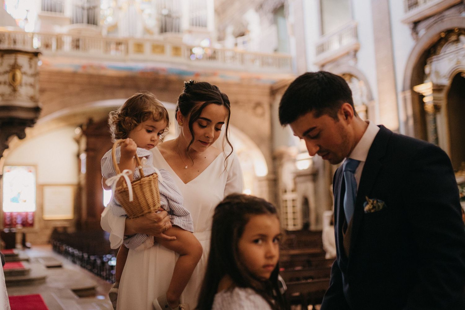 A family moment during a wedding ceremony in an ornate church interior.
