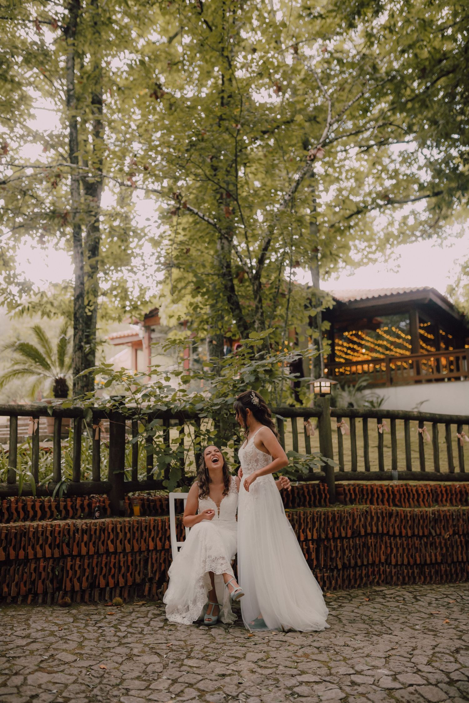 Wedding couple poses on rustic wooden deck surrounded by lush greenery.