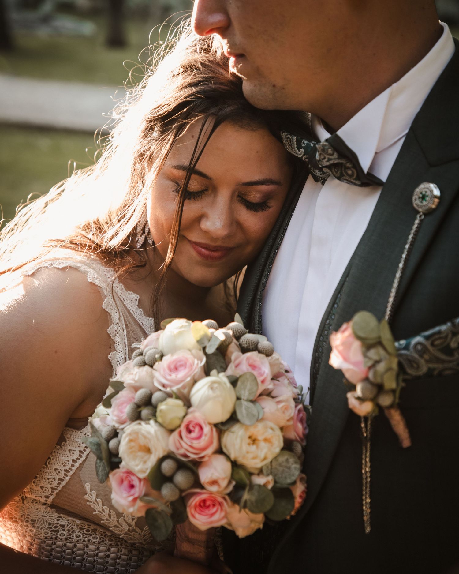 Romantic wedding portrait with pink and white rose bouquet in golden sunlight.