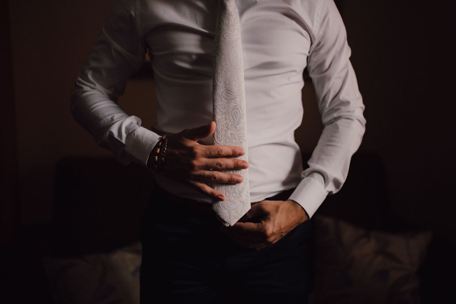 Dramatic lighting on formal white shirt and tie during wedding preparations.