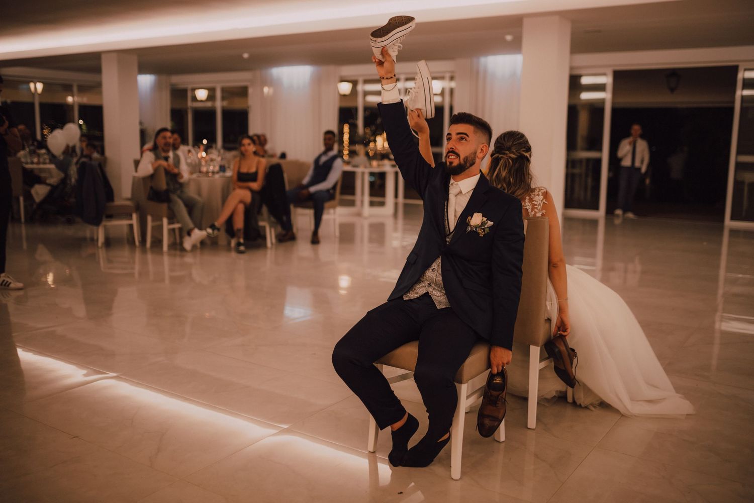 A wedding reception scene showing guests participating in a fun chair-based game or tradition.