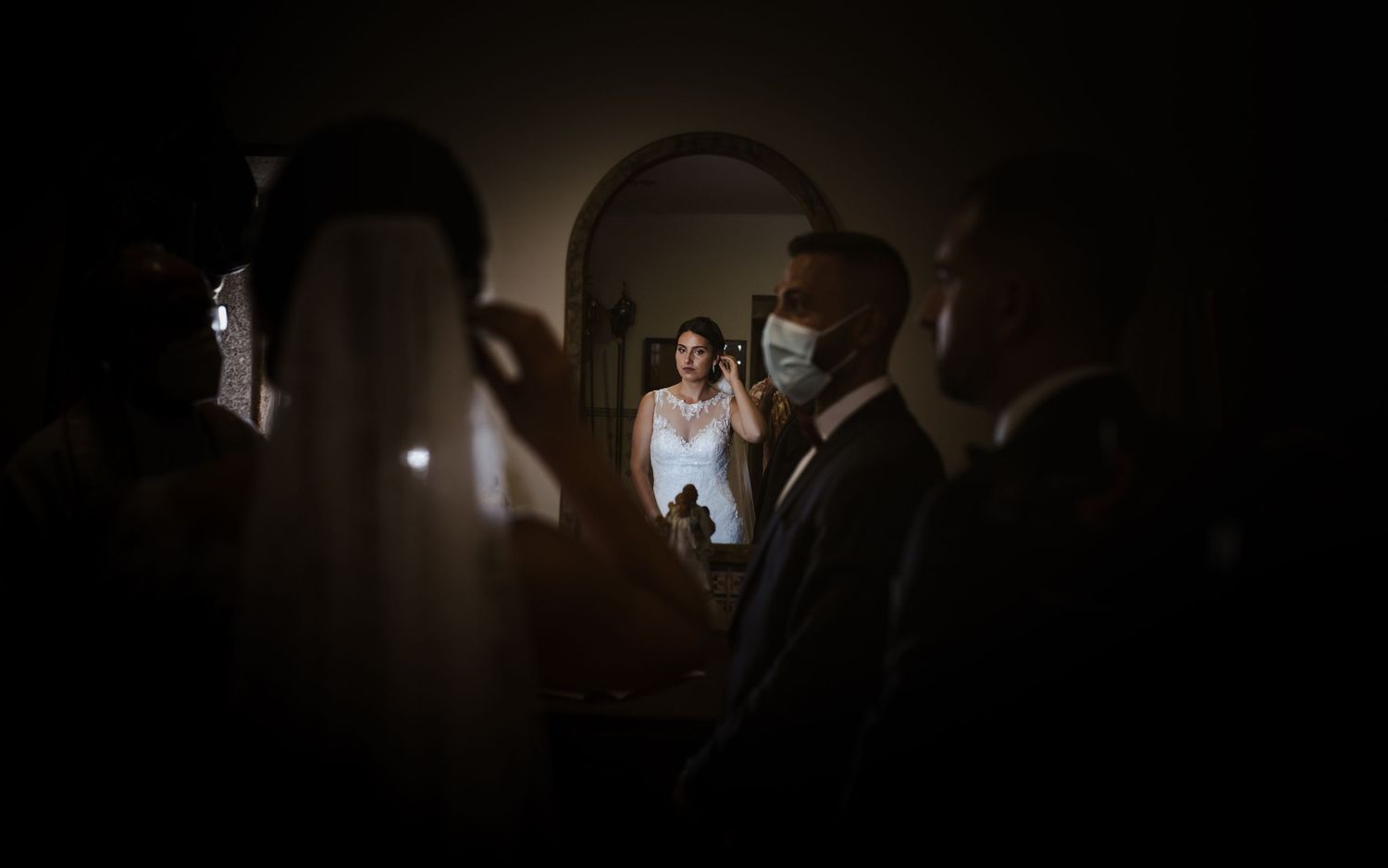 Moody wedding reception photo with guests in dark venue illuminated by soft lighting.