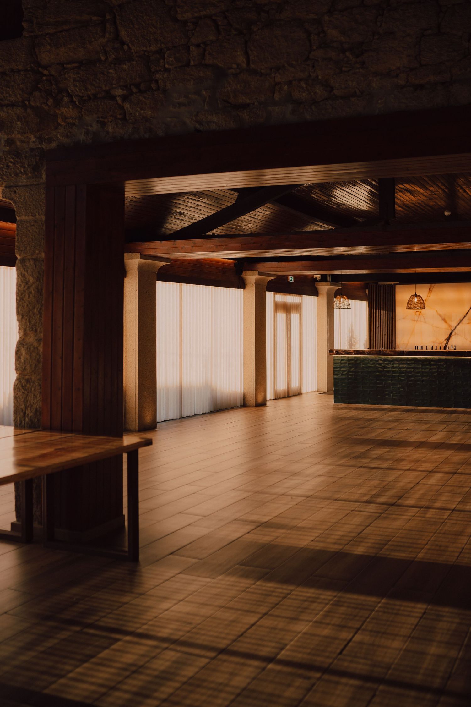Modern empty event venue with wood accents and stone walls illuminated in warm lighting.
