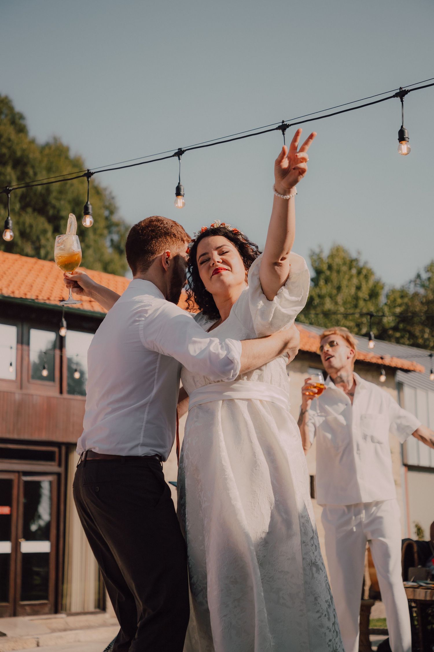 Couple dancing outdoors under string lights during wedding celebration.